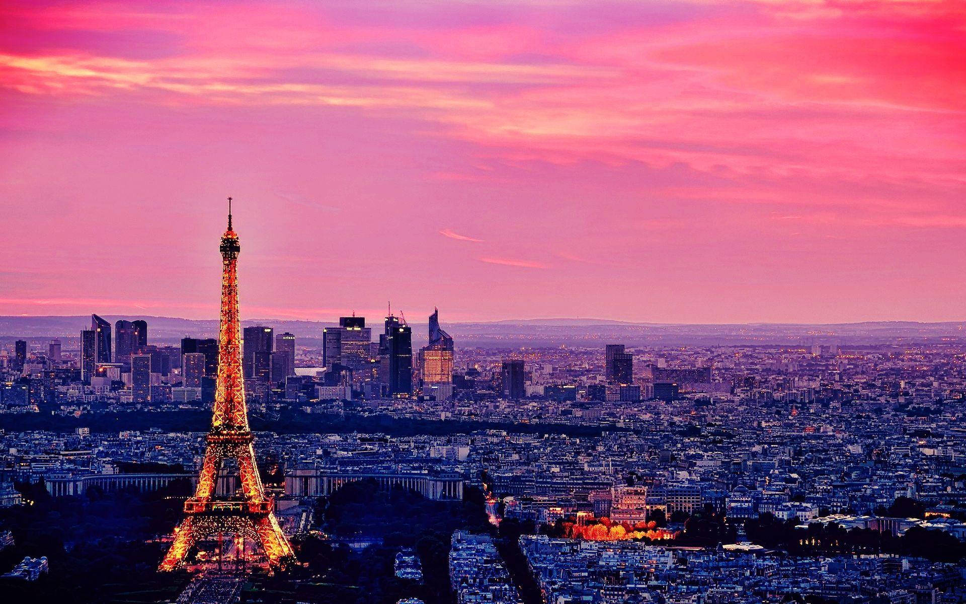 Paris Eiffel Tower 桌布 壁紙 — 黃昏時分的巴黎天際線，艾菲爾鐵塔在充滿活力的粉紅色和紫色天空中閃耀。