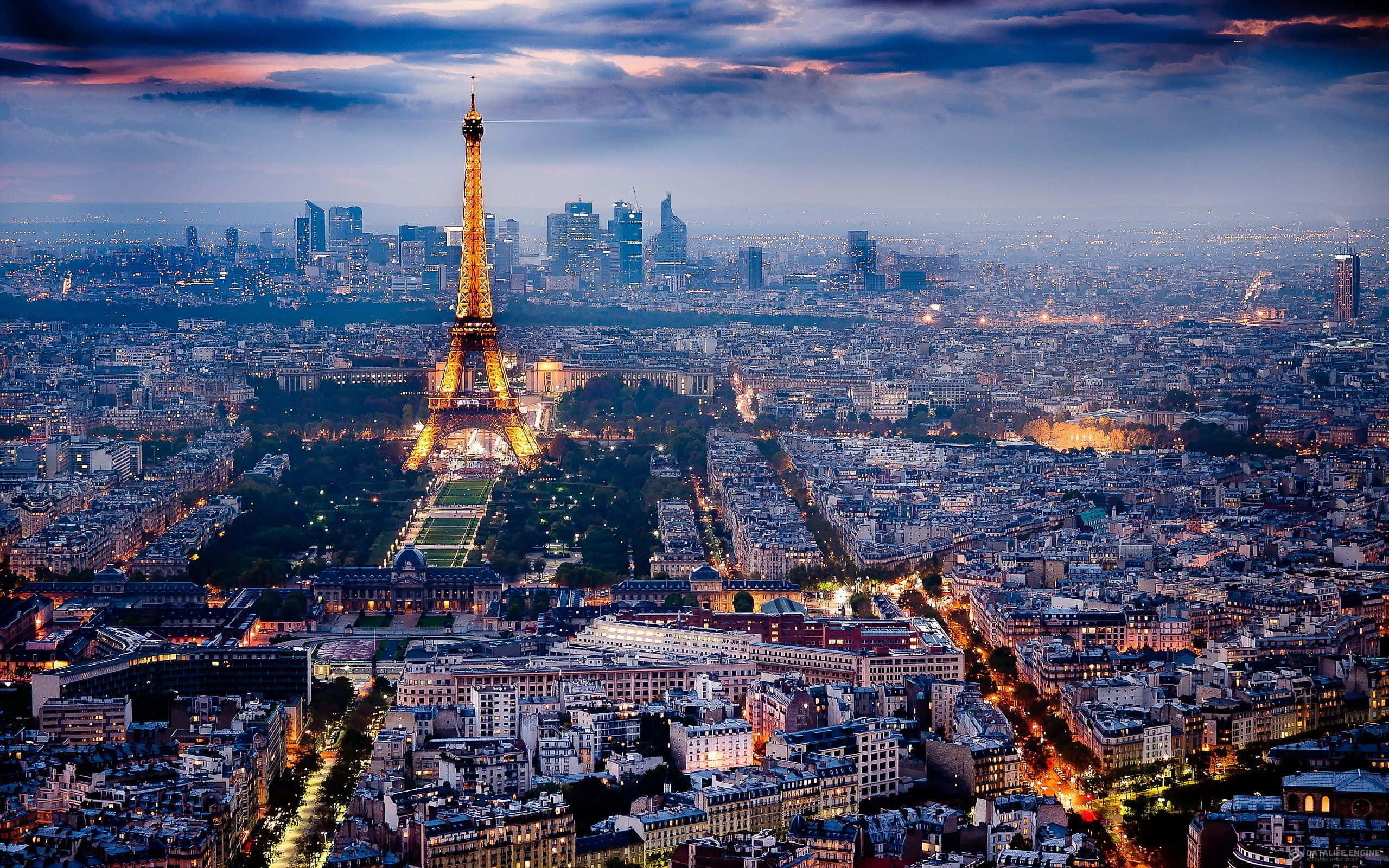 french 桌布 壁紙 — 黃昏時分的巴黎天際線，艾菲爾鐵塔在憂鬱的紫色天空映襯下閃耀著金色光芒。