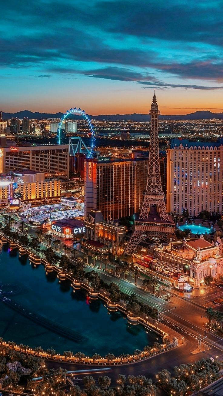 Las Vegas 桌布 壁紙 — 黃昏時分的拉斯維加斯天際線，閃爍的酒店和複製的艾菲爾鐵塔在戲劇性的藍天下。