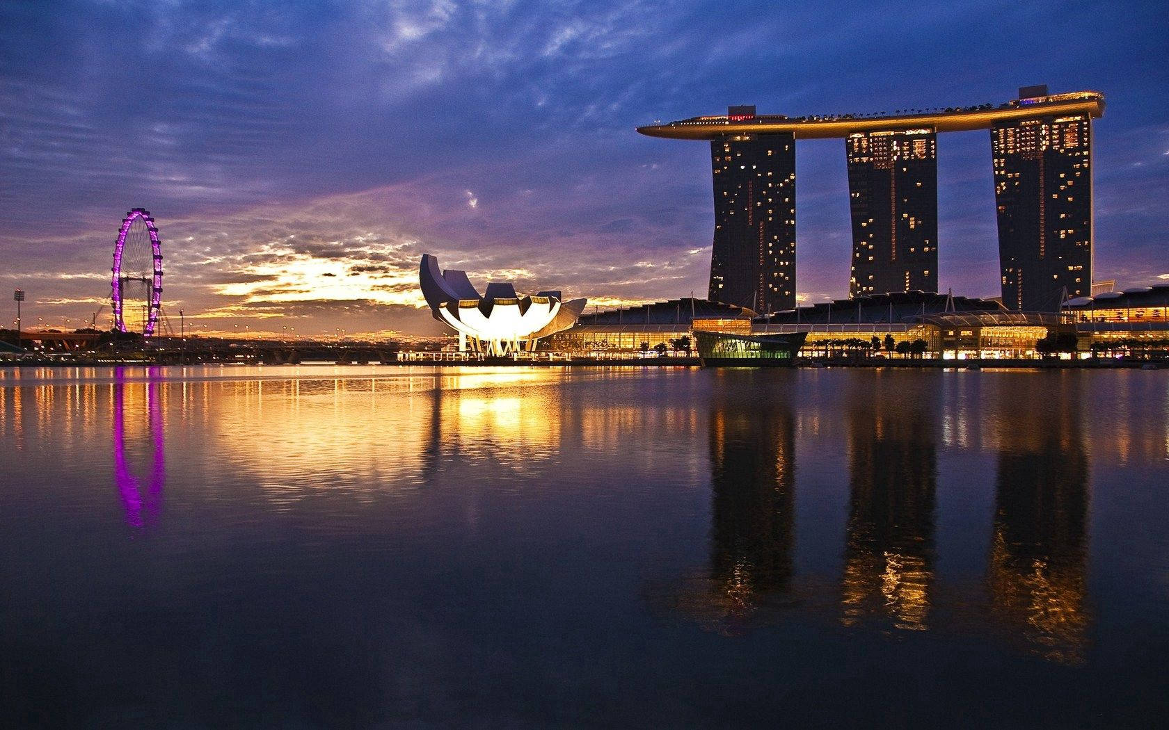 Singapore 桌布 壁紙 — 黃昏時分的新加坡天際線，濱海灣金沙和新加坡摩天輪在平靜的水面上倒映，天空呈現紫橙色。