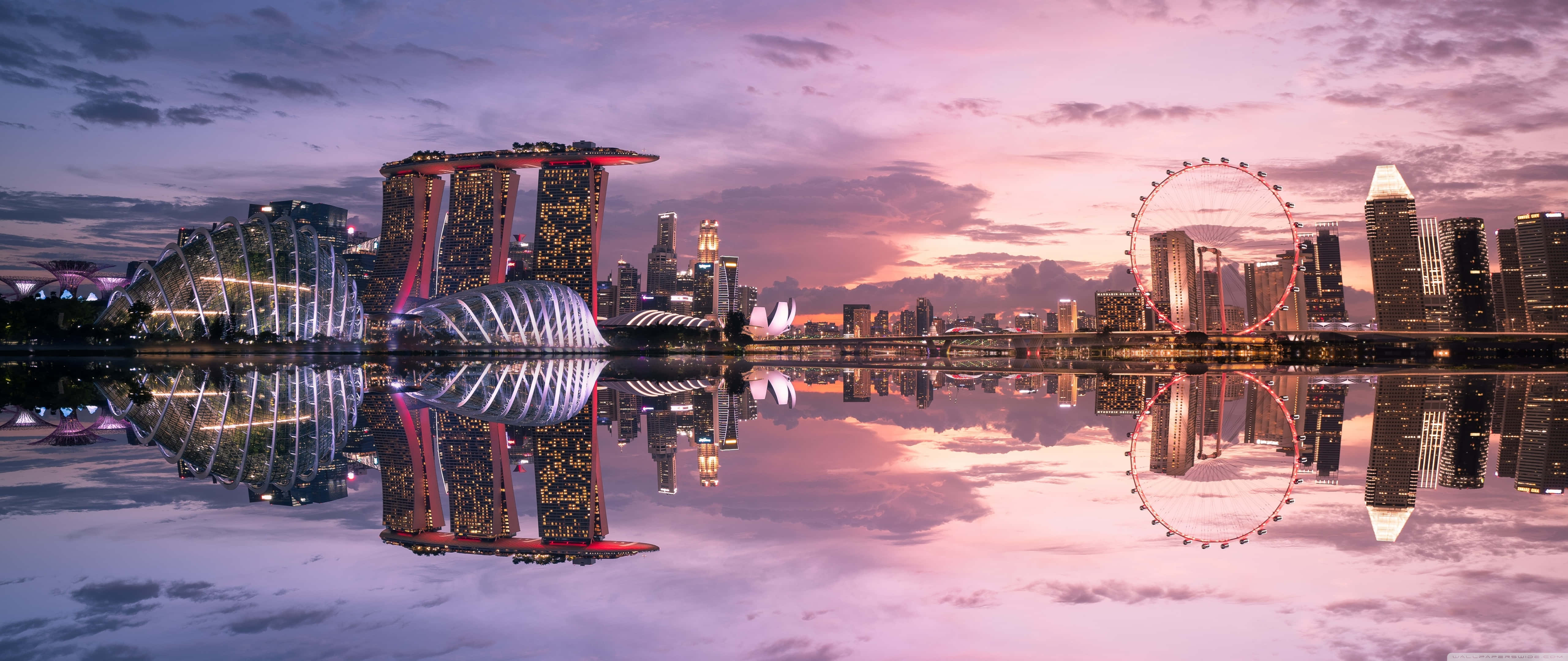 Ultra Wide 桌布 壁紙 — 黃昏時分的新加坡天際線，濱海灣金沙和新加坡摩天觀景輪在粉紫色天空下平靜的水面上倒映。