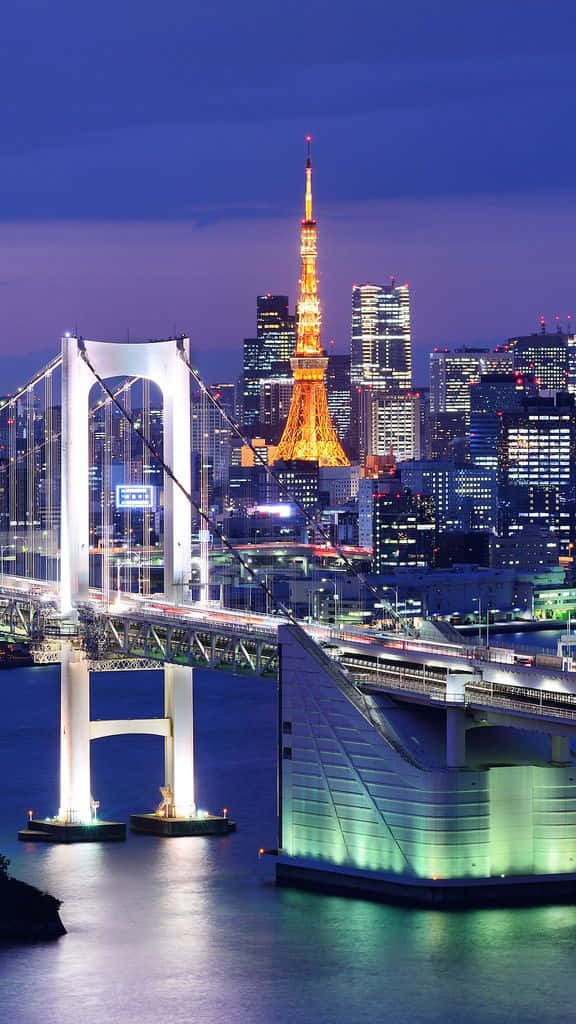 Rainbow Bridge 桌布 壁紙 — 黃昏時分的東京天際線，彩虹橋和東京塔在平靜的水面上閃爍倒影。