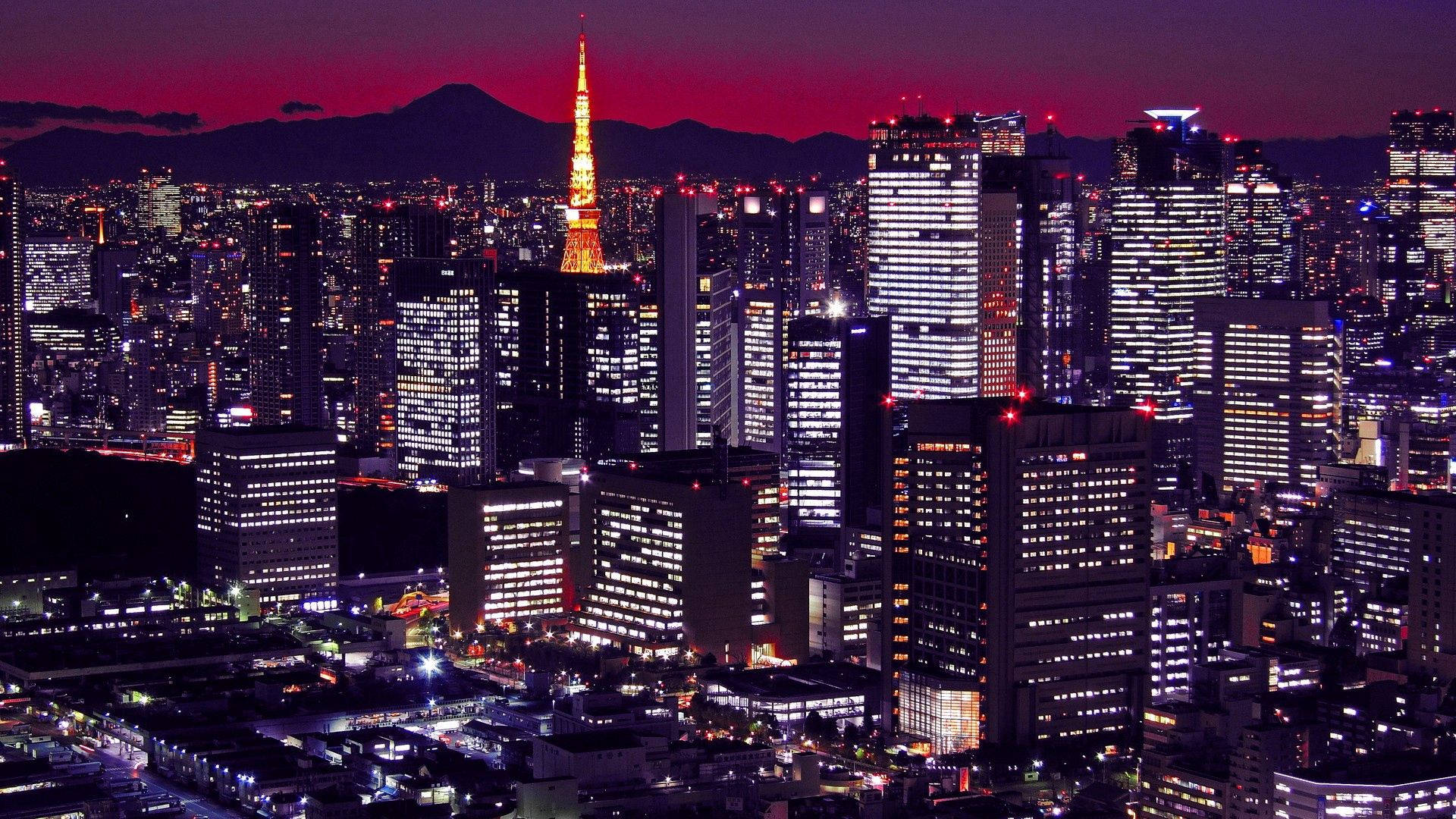 日本 桌布 壁紙 — 黃昏時分的東京天際線，閃爍的摩天大樓和富士山在火紅的天空中映襯出剪影。