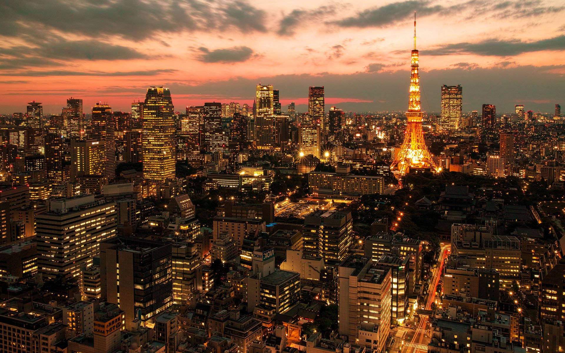 日本 桌布 壁紙 — 黃昏時分的東京天際線，閃耀的東京鐵塔和城市燈光映襯著火紅的橙色和粉紅色天空。