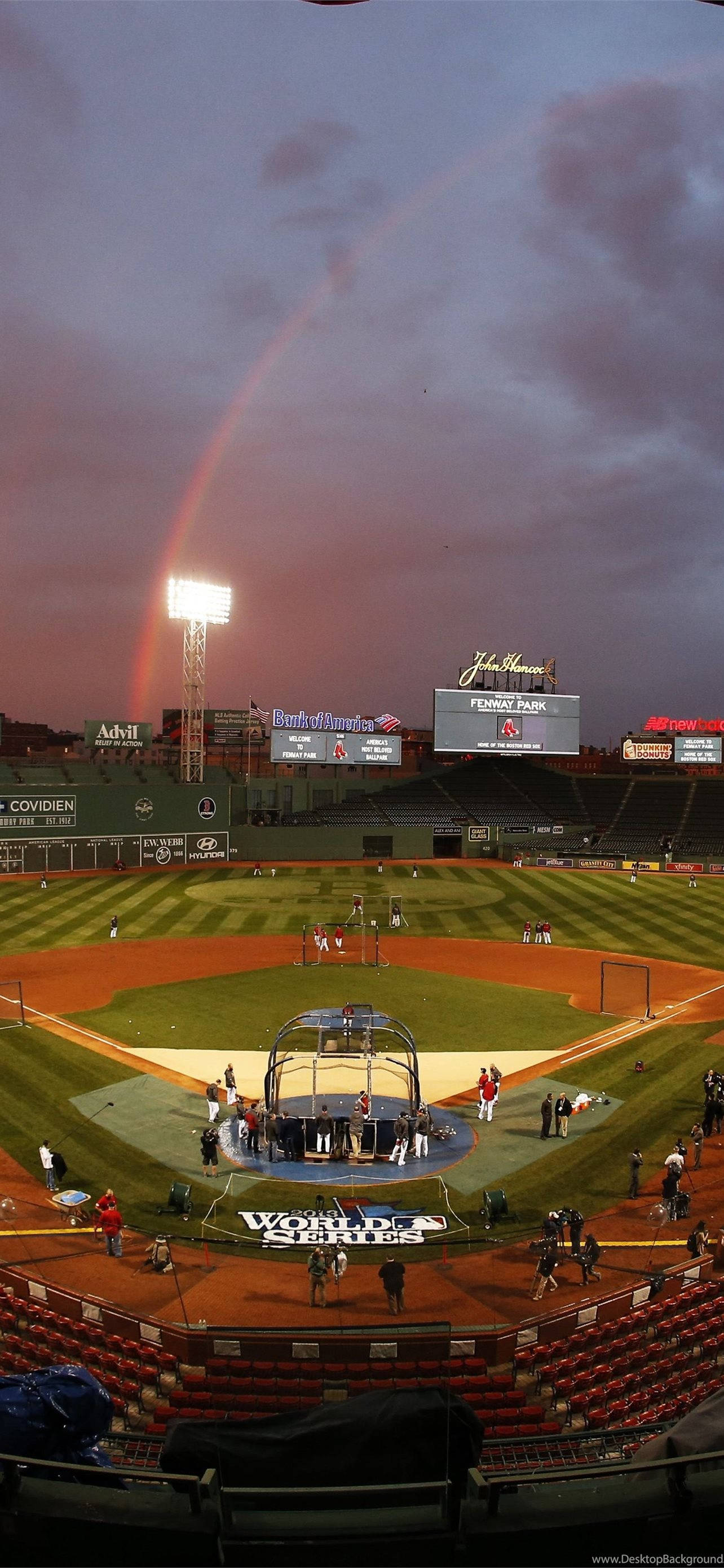 Red Sox 桌布 壁紙 — 黃昏時分的棒球場，一道鮮豔的彩虹拱在球場上方，球員和工作人員聚集在世界大賽標誌附近。