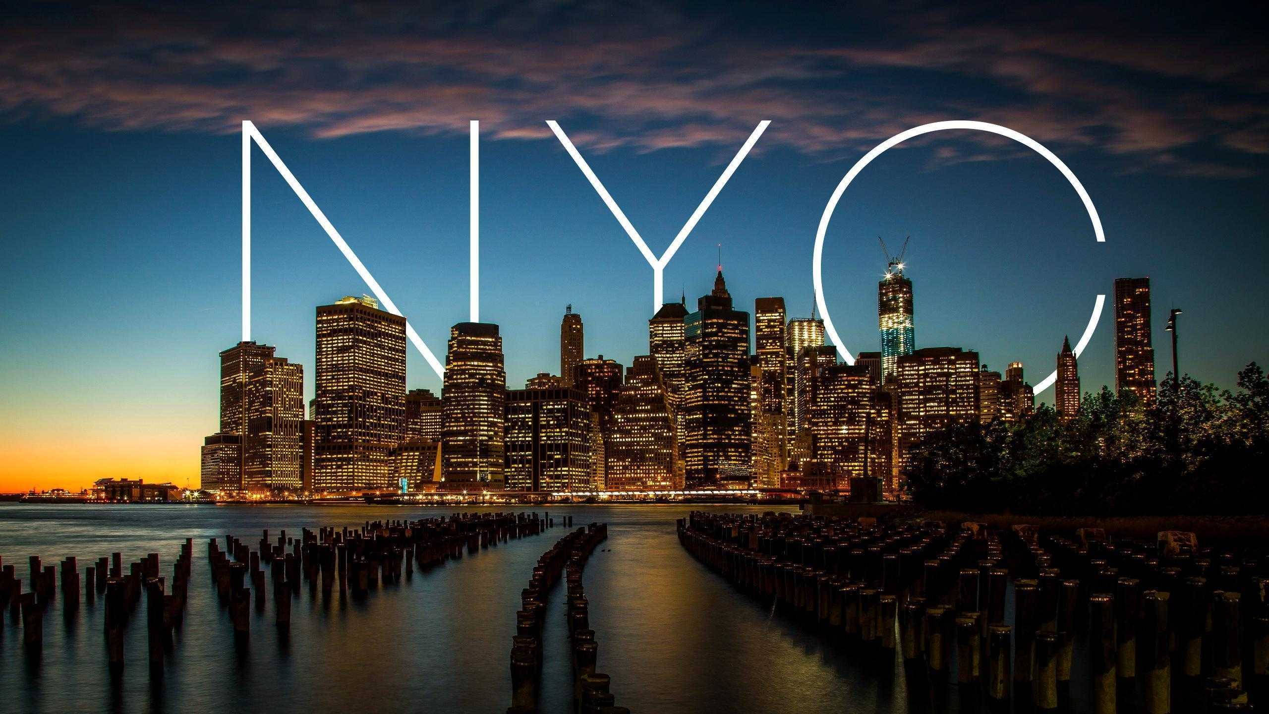 New 桌布 壁紙 — 黃昏時分的紐約市天際線，發光的「NYC」字母疊加在燈火通明的摩天大樓和水面上。