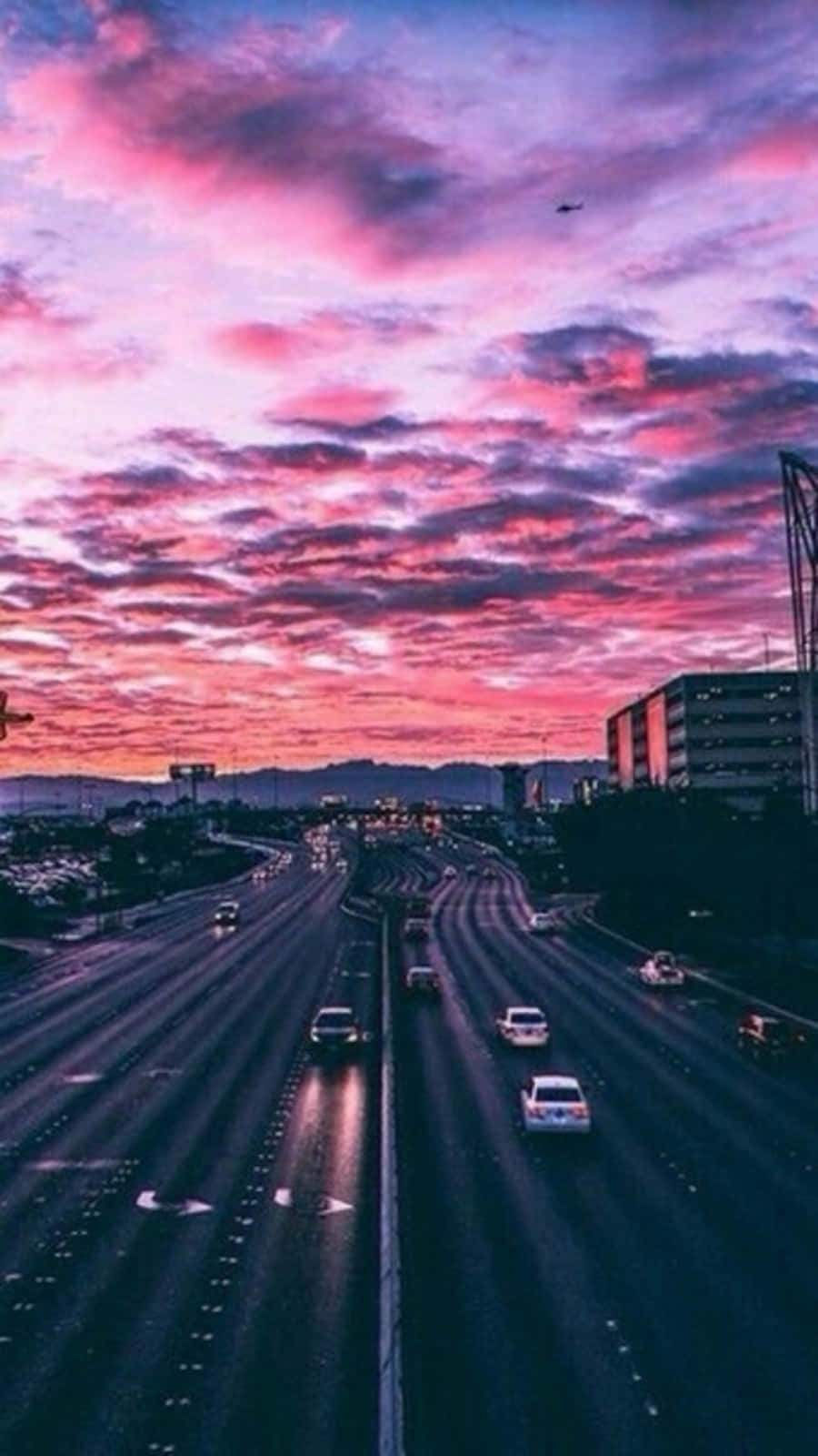 Tumblr 桌布 壁紙 — 黃昏時分的高速公路，汽車在充滿活力的粉紅色和紫色天空下行駛，天空中有散落的雲。