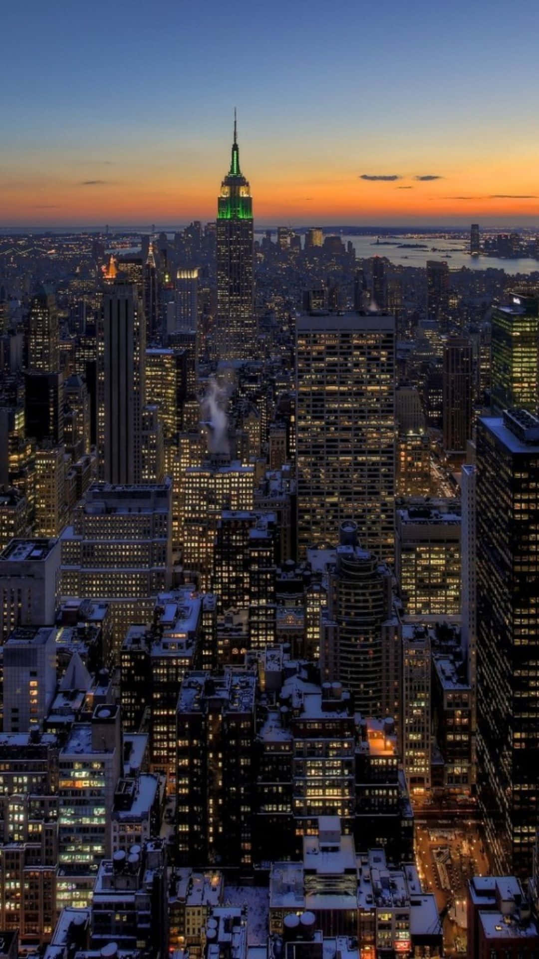 Android Ny City 桌布 壁紙 — 黃昏時分積雪的紐約市天際線，帝國大廈在漸層的天空中發出綠光。