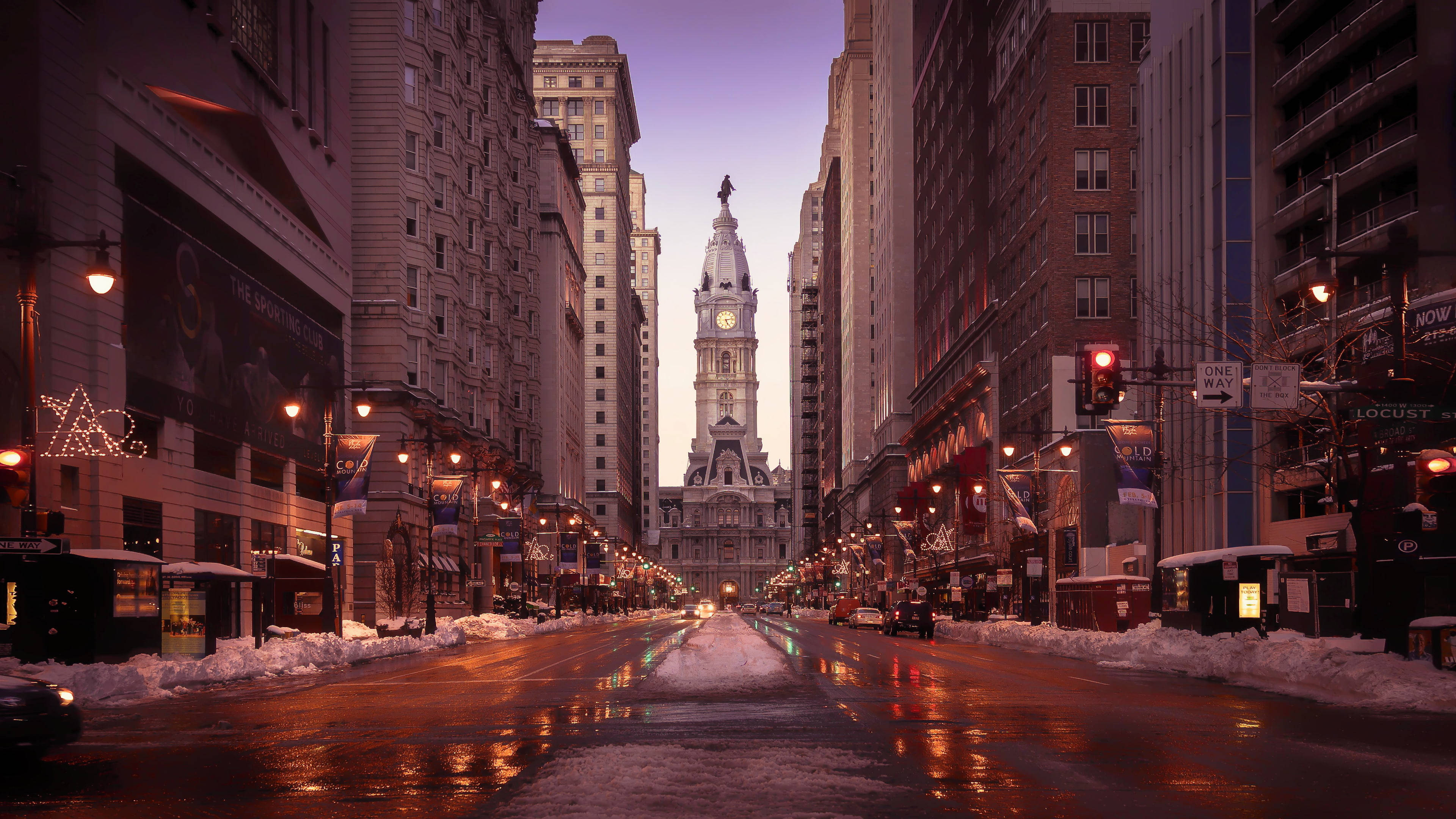 Philadelphia 桌布 壁紙 — 黃昏時分積雪的都市街道，潮濕的路面反射著溫暖的路燈和遠處高聳的鐘樓。