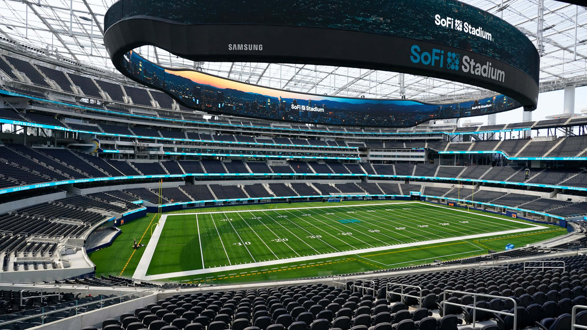 Stadium 桌布 壁紙 — 黃昏時分空無一人的SoFi體育場鳥瞰圖，藍色燈光閃爍，綠色球場生機勃勃。