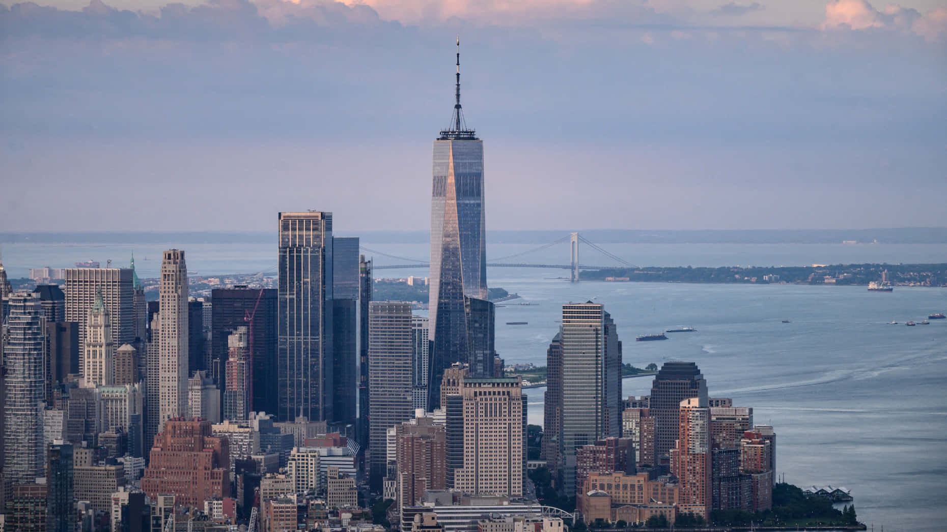Wall Street 桌布 壁紙 — 黃昏時分紐約市天際線的全景，世界貿易中心一號大樓聳立在摩天大樓和下方的哈德遜河之上。