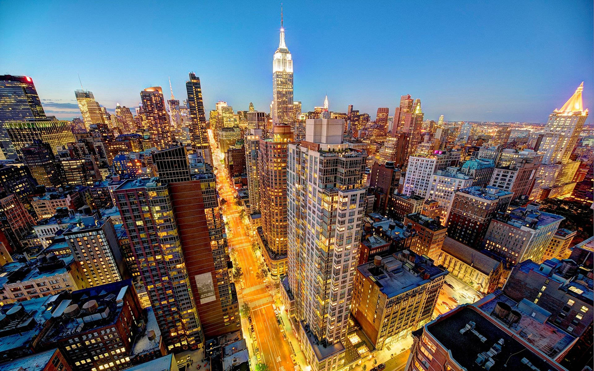 New York City Desktop 桌布 壁紙 — 黃昏時分紐約市天際線的鳥瞰圖，下方是燈火通明的摩天大樓和閃爍的街道。