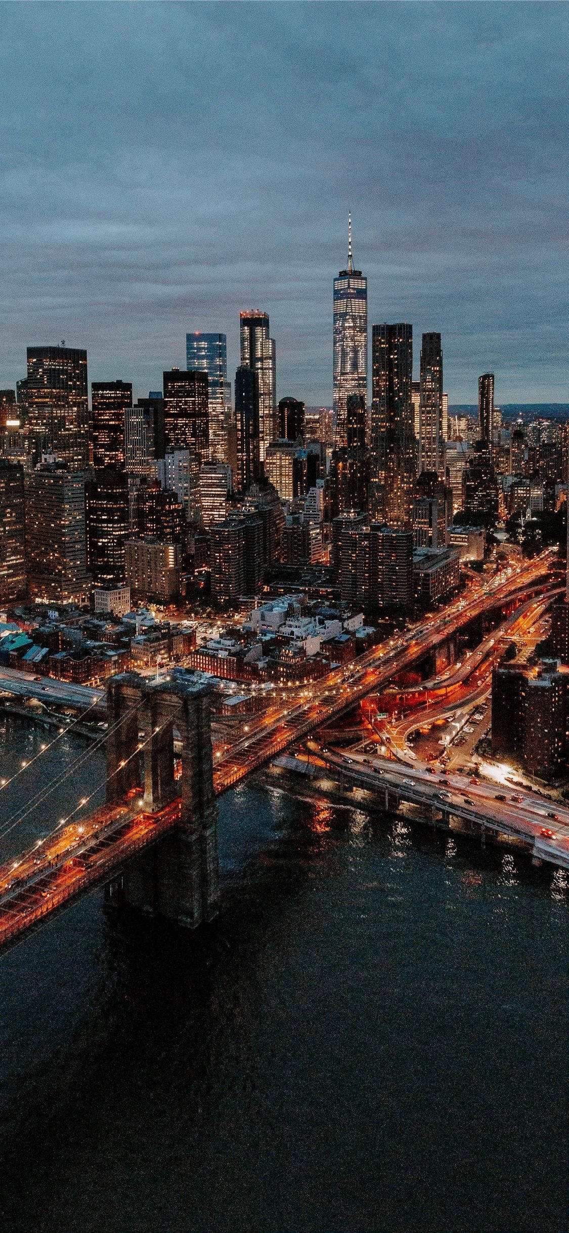 New York 桌布 壁紙 — 黃昏時分紐約市天際線的鳥瞰圖，燈火通明的摩天大樓和布魯克林大橋橫跨水面。