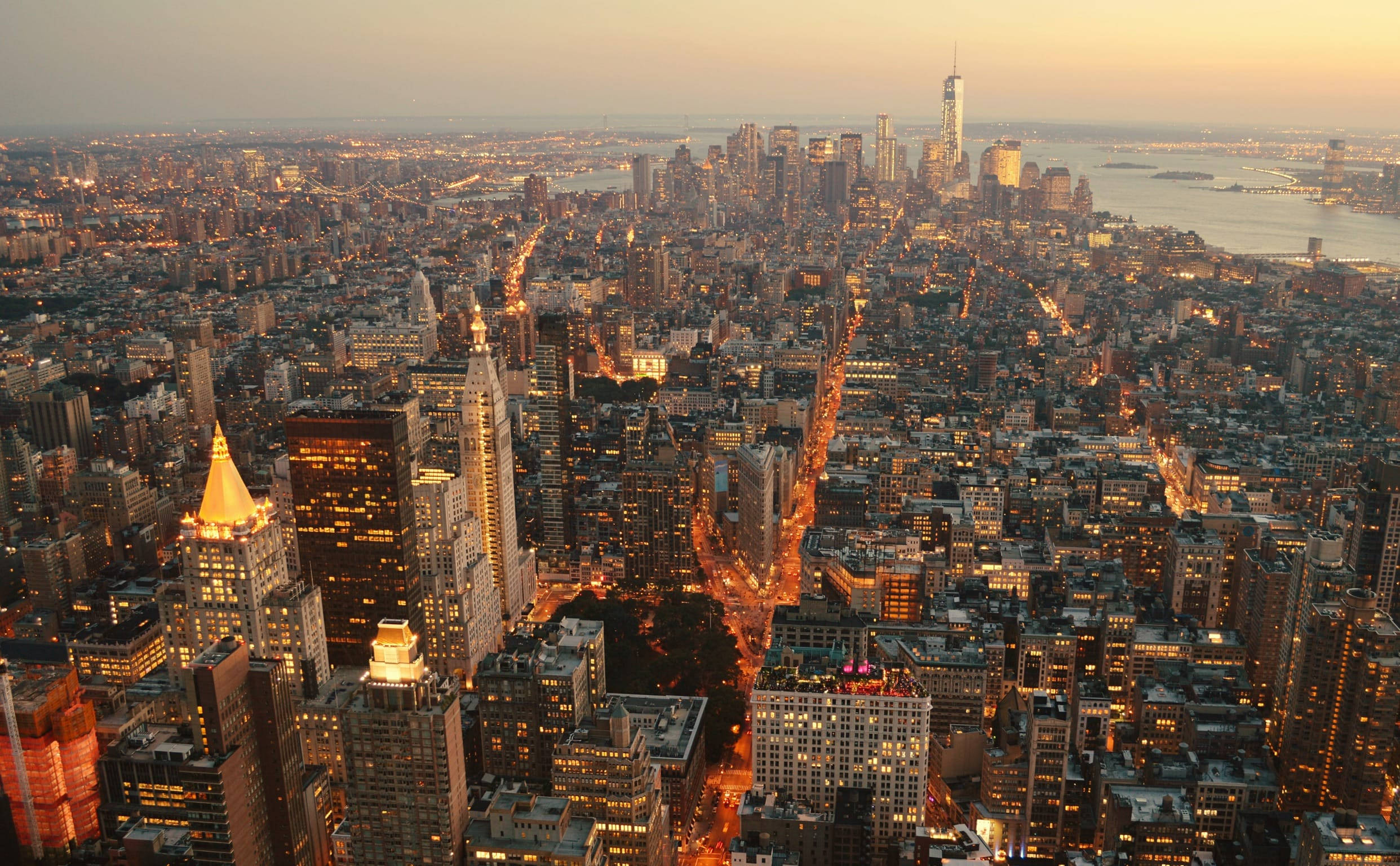 empire state 桌布 壁紙 — 黃昏時分紐約市的鳥瞰圖，摩天大樓和街道上閃爍著金色的燈光。
