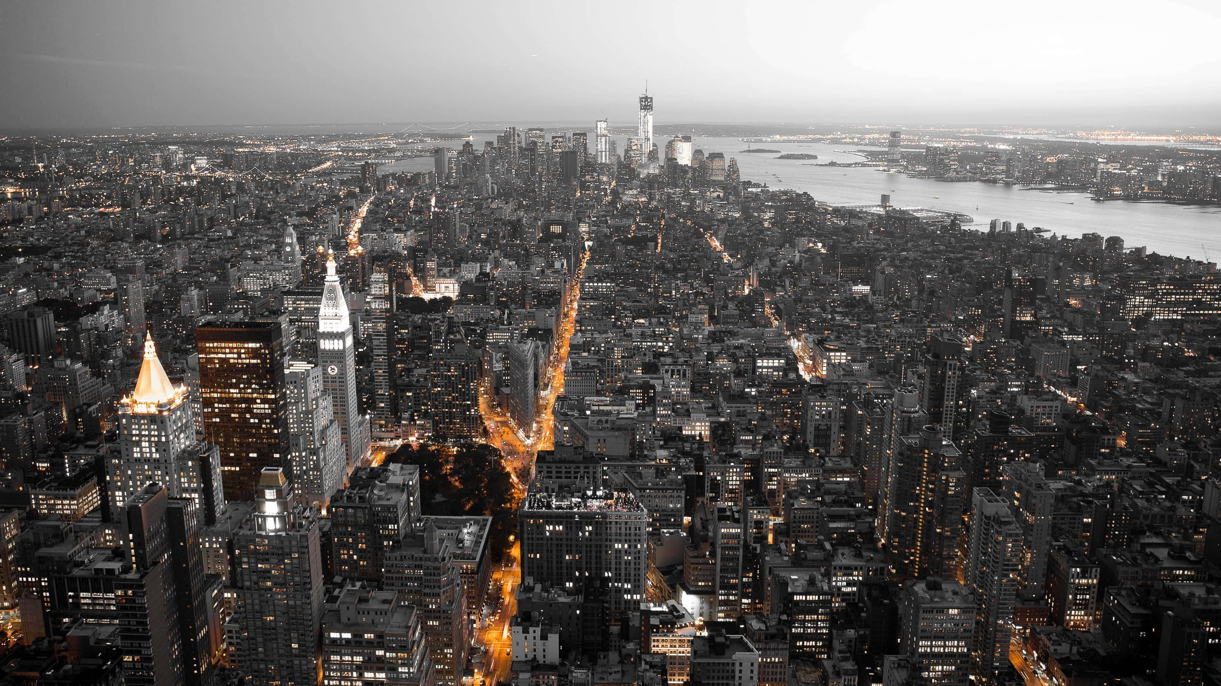 4K Resolution 桌布 壁紙 — 黃昏時分紐約市的鳥瞰圖，選擇性色彩突出金色的街燈和標誌性摩天大樓，與單色天際線形成對比。