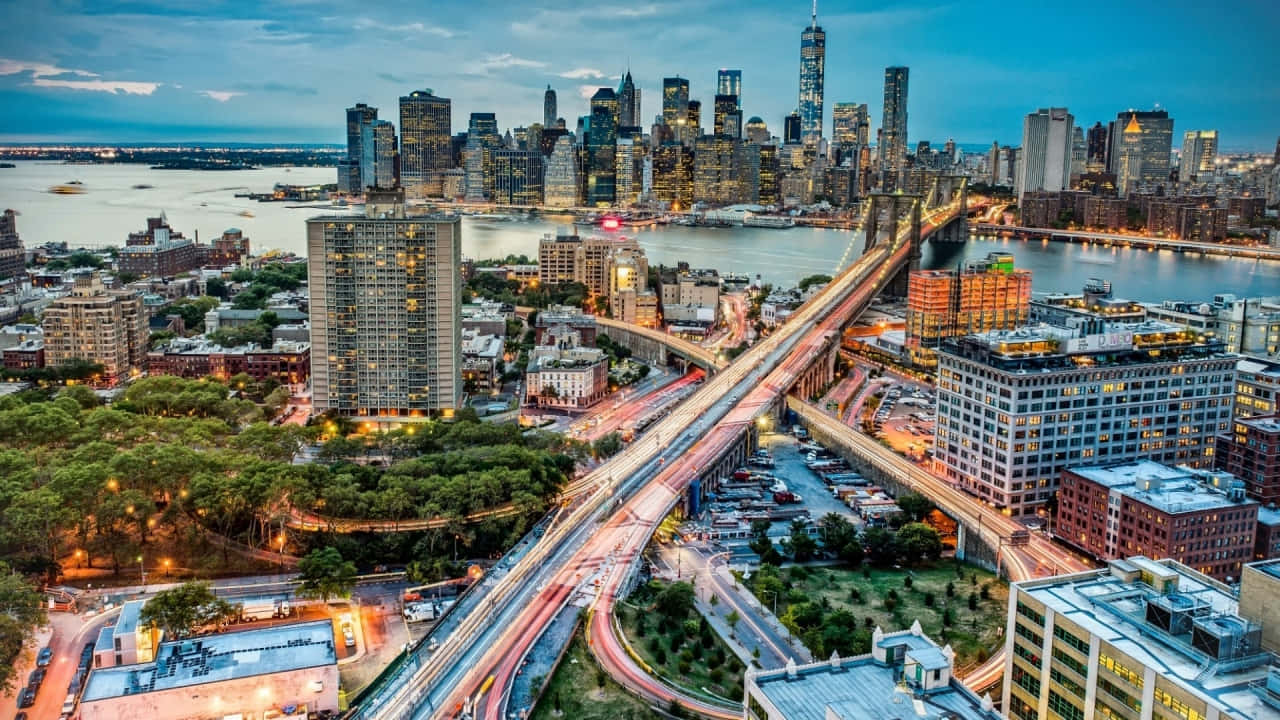 720p Ny City 桌布 壁紙 — 黃昏時分紐約市的鳥瞰圖，閃爍的摩天大樓和水上橋樑上交通的光跡。