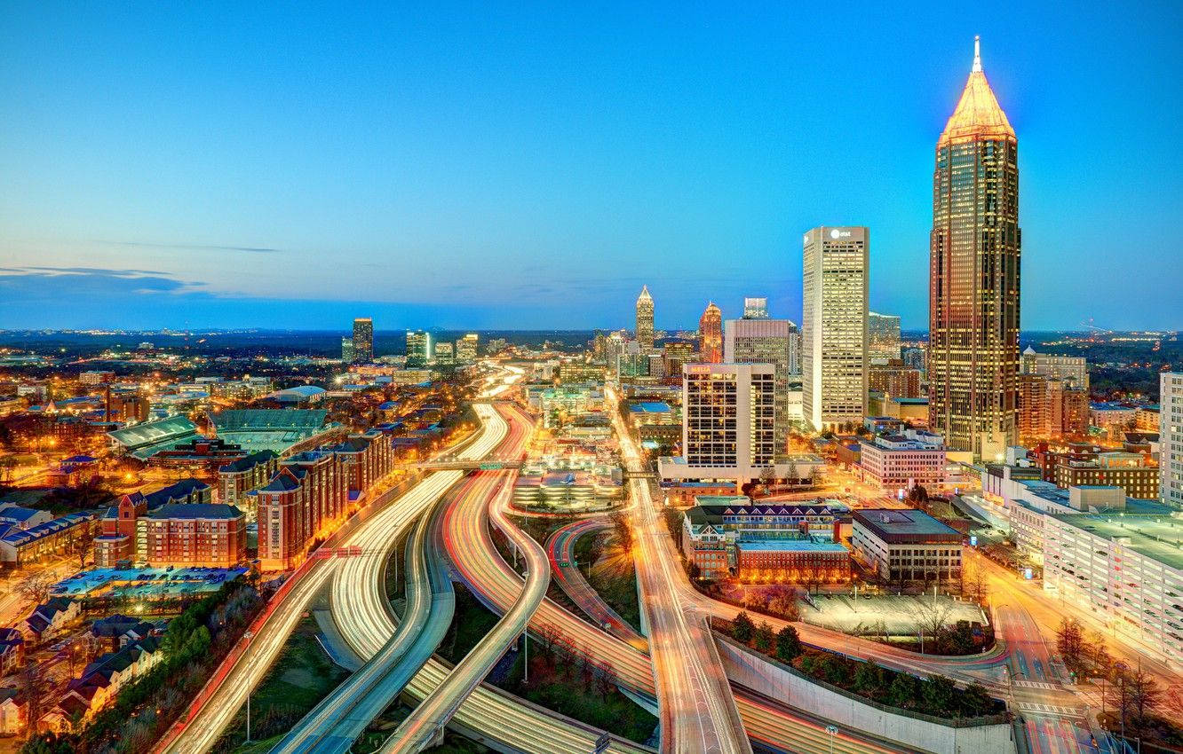 Atlanta 桌布 壁紙 — 黃昏時分繁忙城市景觀的鳥瞰圖，閃爍的摩天大樓和蜿蜒高速公路上的車流光軌。