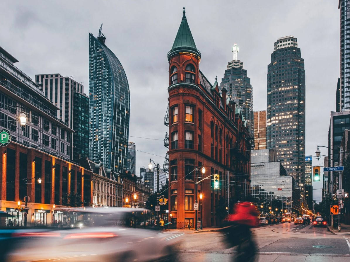 Ontario 桌布 壁紙 — 黃昏時分繁忙的城市街道，歷史悠久的紅磚建築和現代玻璃摩天大樓被街燈和車頭燈照亮。