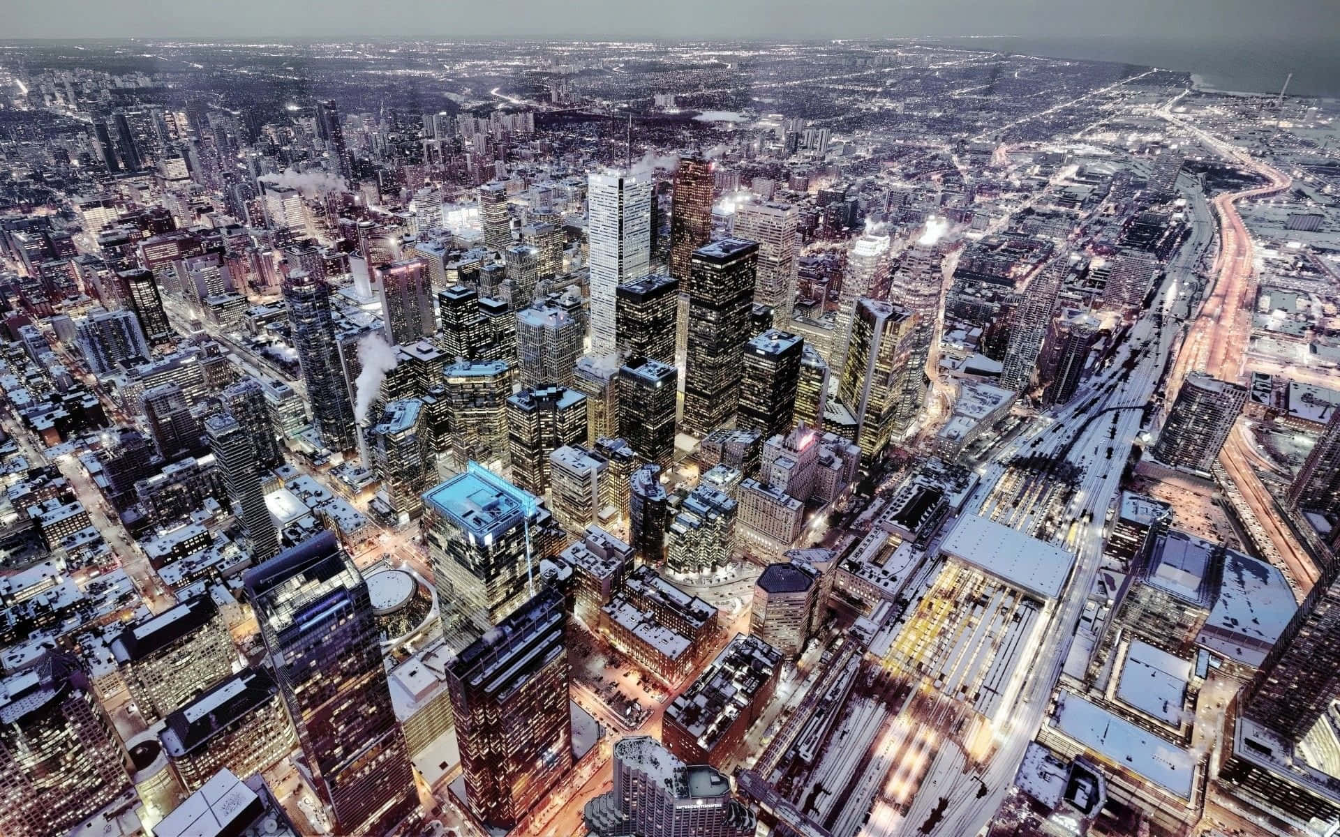 Toronto 桌布 壁紙 — 黃昏時分被雪覆蓋的城市景觀鳥瞰圖，高樓大廈燈火通明，街道閃爍。