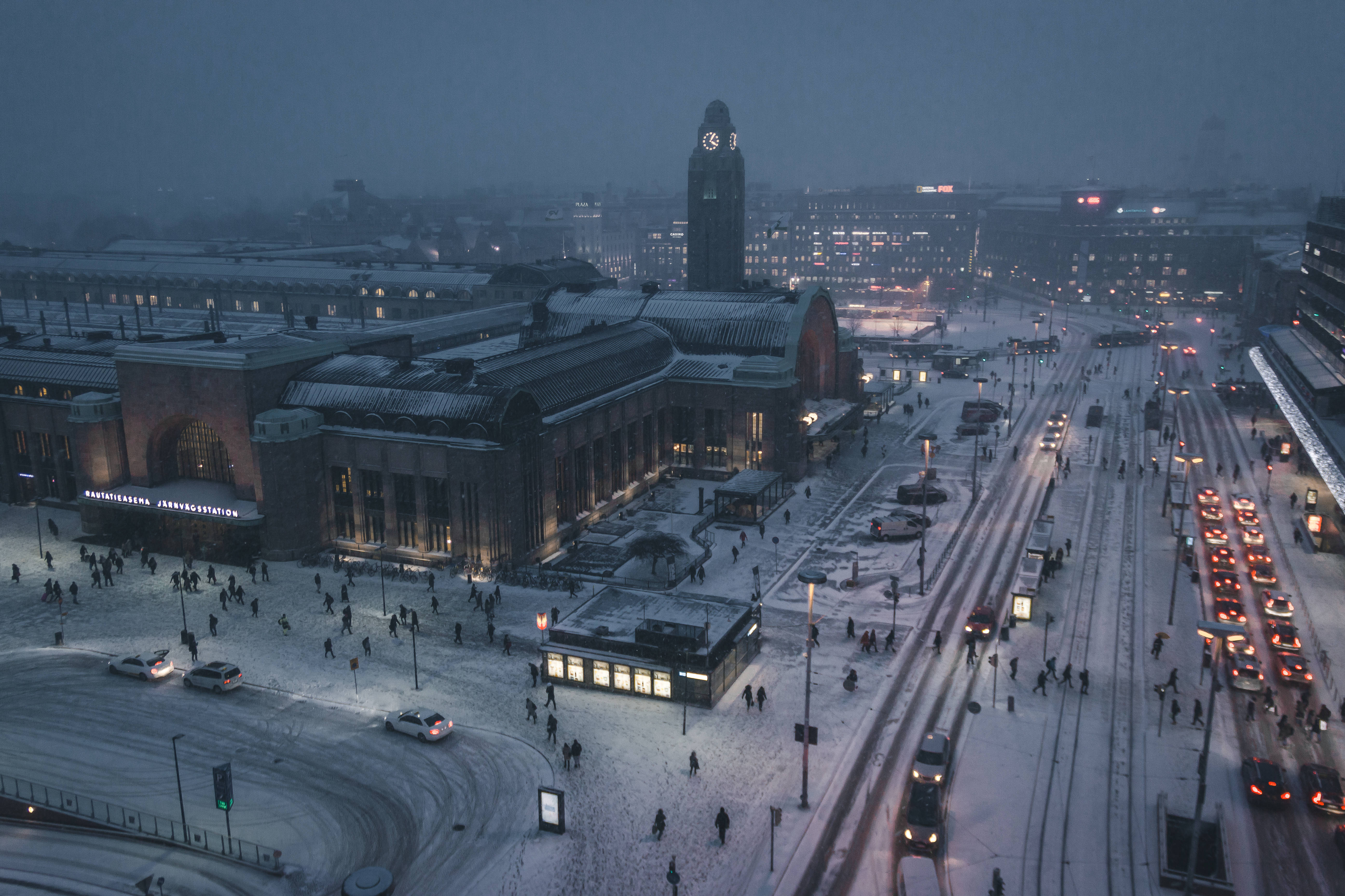 Finland 桌布 壁紙 — 黃昏時分被雪覆蓋的火車站鳥瞰圖，燈光閃爍，道路繁忙。