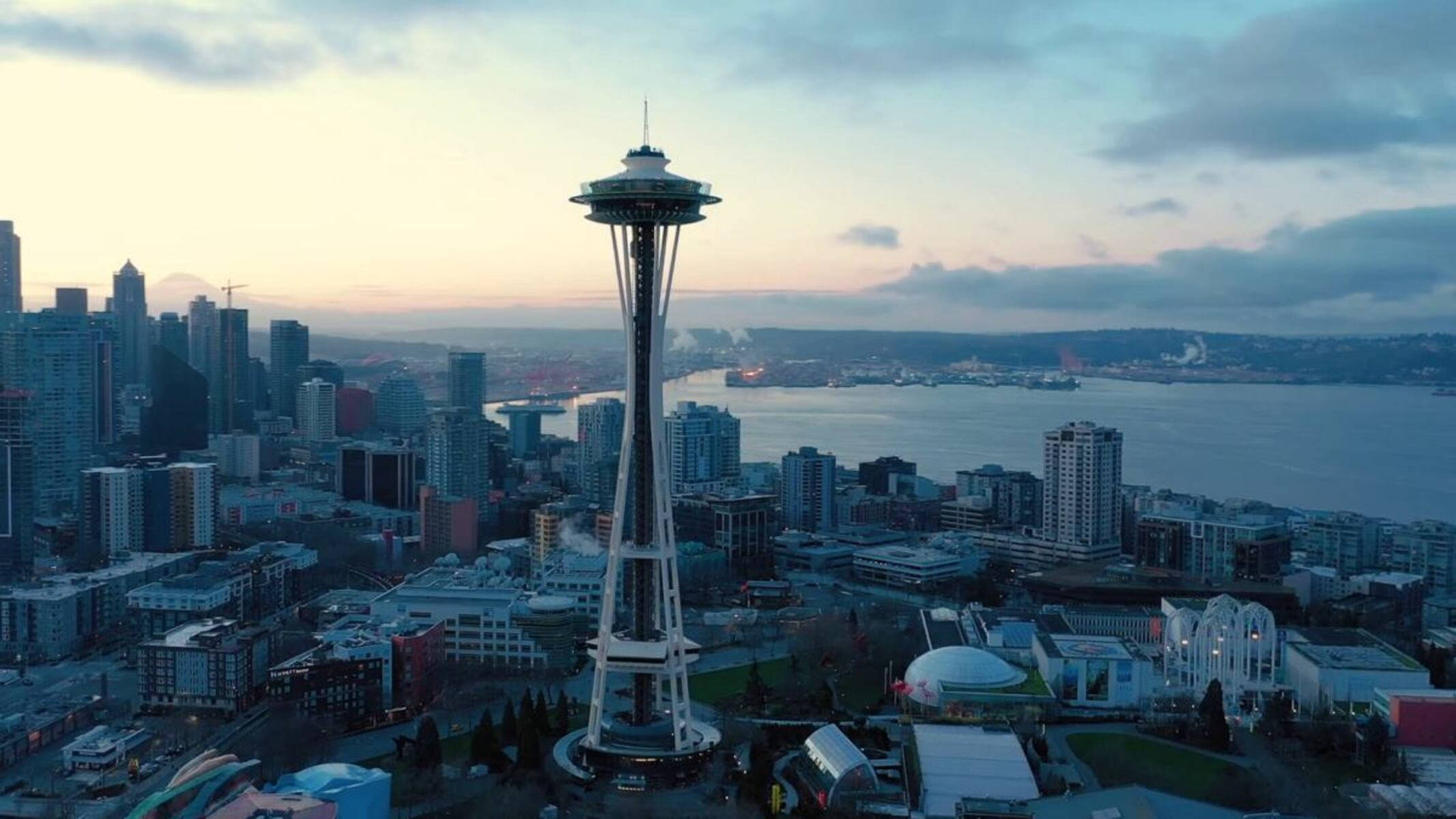 Seattle Skyline 桌布 壁紙 — 黃昏時分西雅圖太空針塔的鳥瞰圖，城市天際線和海濱在柔和粉彩天空下閃耀。