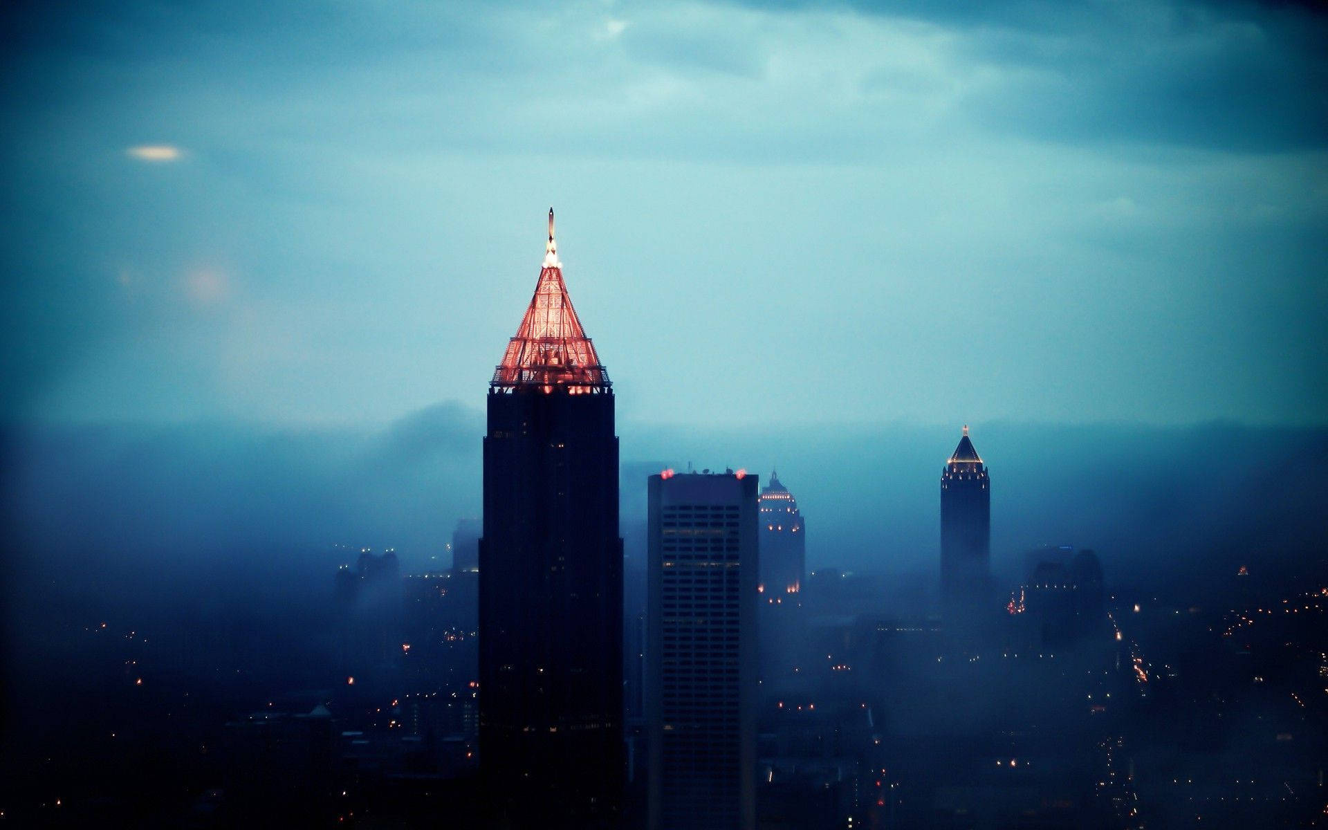 Atlanta 桌布 壁紙 — 黃昏時分霧氣瀰漫的城市天際線，高聳的摩天大樓在清冷的藍天下溫暖地發光。