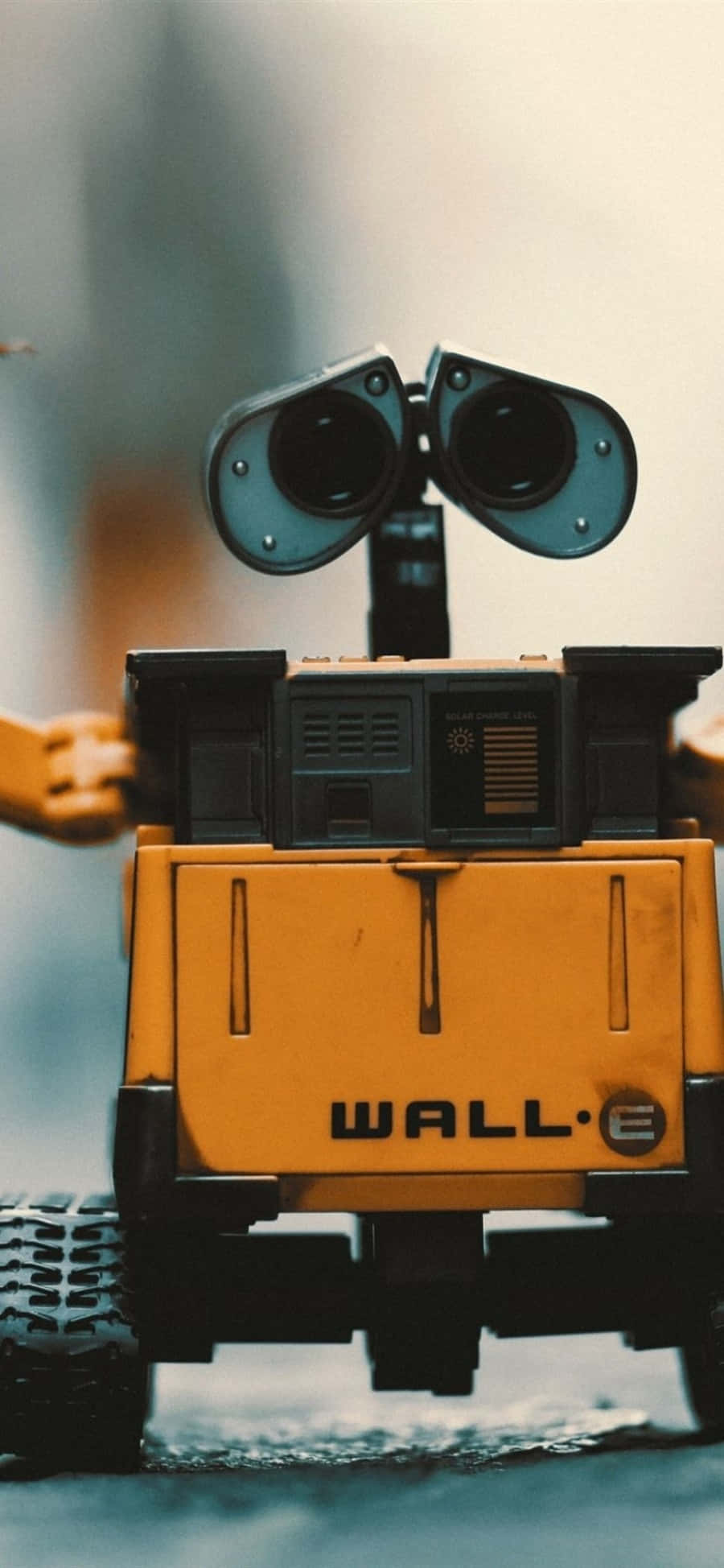 Wall E 桌布 壁紙 — 黃色WALL-E玩具機器人特寫，具有大型雙筒望遠鏡眼睛和可見的「WALL·E」品牌標誌。