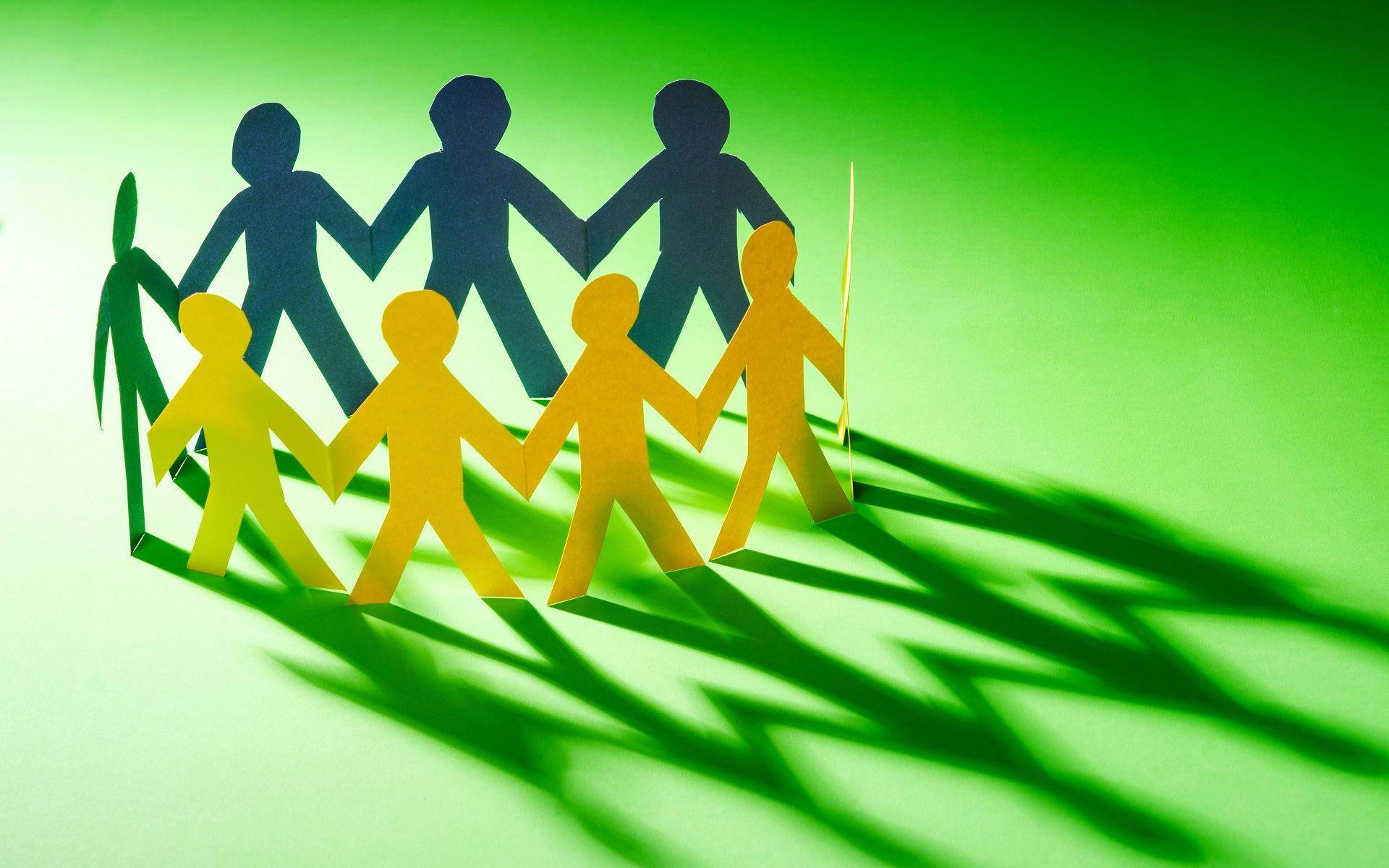 Teamwork 桌布 壁紙 — 黃色和深藍色的紙剪影人物手牽手圍成一個圓圈，在充滿活力的綠色背景上投下長長的陰影。