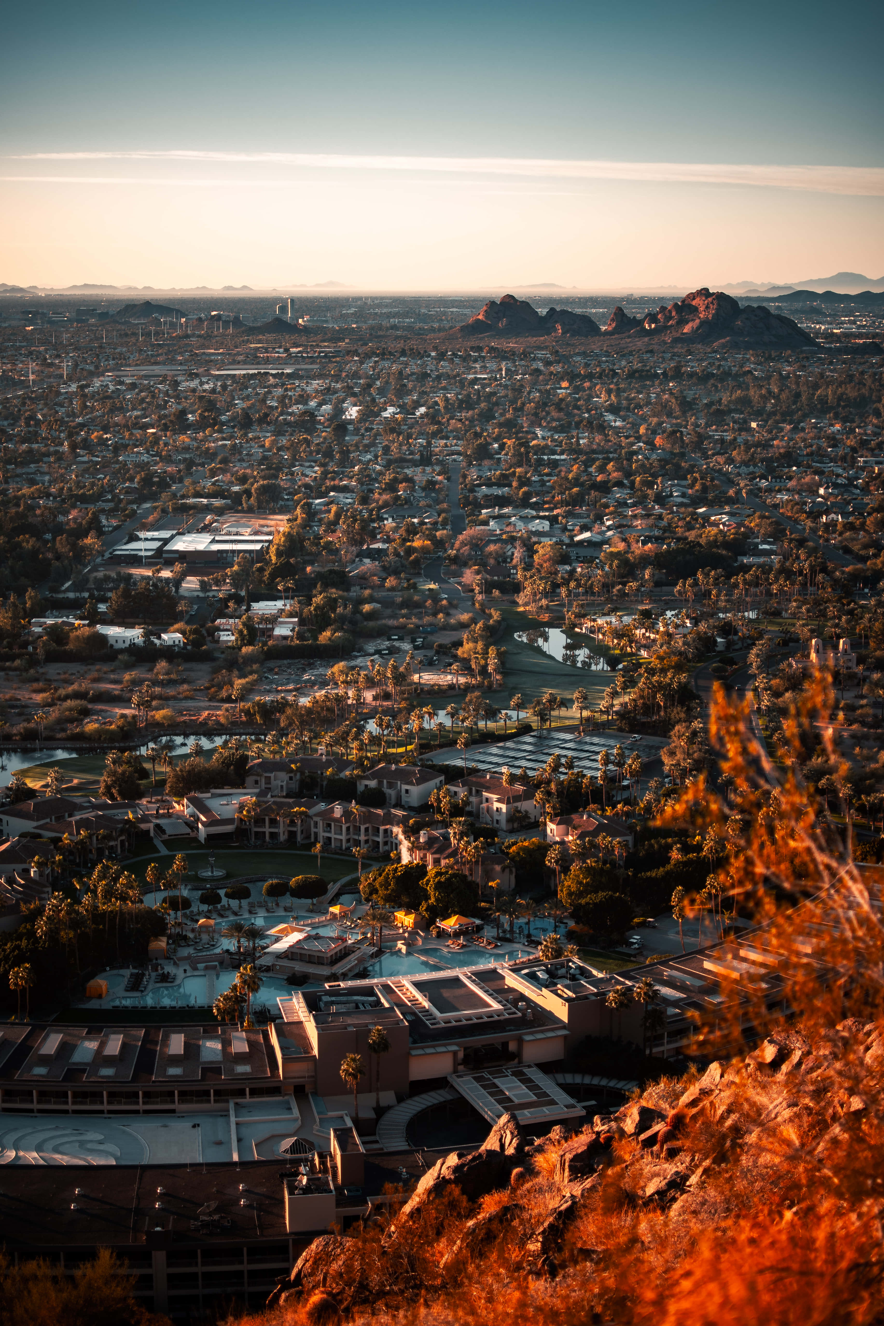 Phoenix Arizona 桌布 壁紙 — 黃金時分廣闊沙漠城市的鳥瞰圖，遠方有紅色岩層和溫暖的橙色色調。