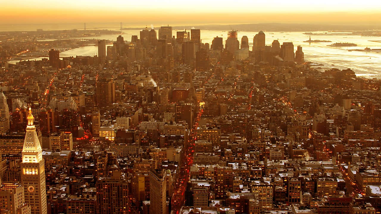 720p Empire State Building 桌布 壁紙 — 黃金時刻以溫暖的琥珀色光芒沐浴著密集的城市天際線，城市的燈光開始在下方閃爍。