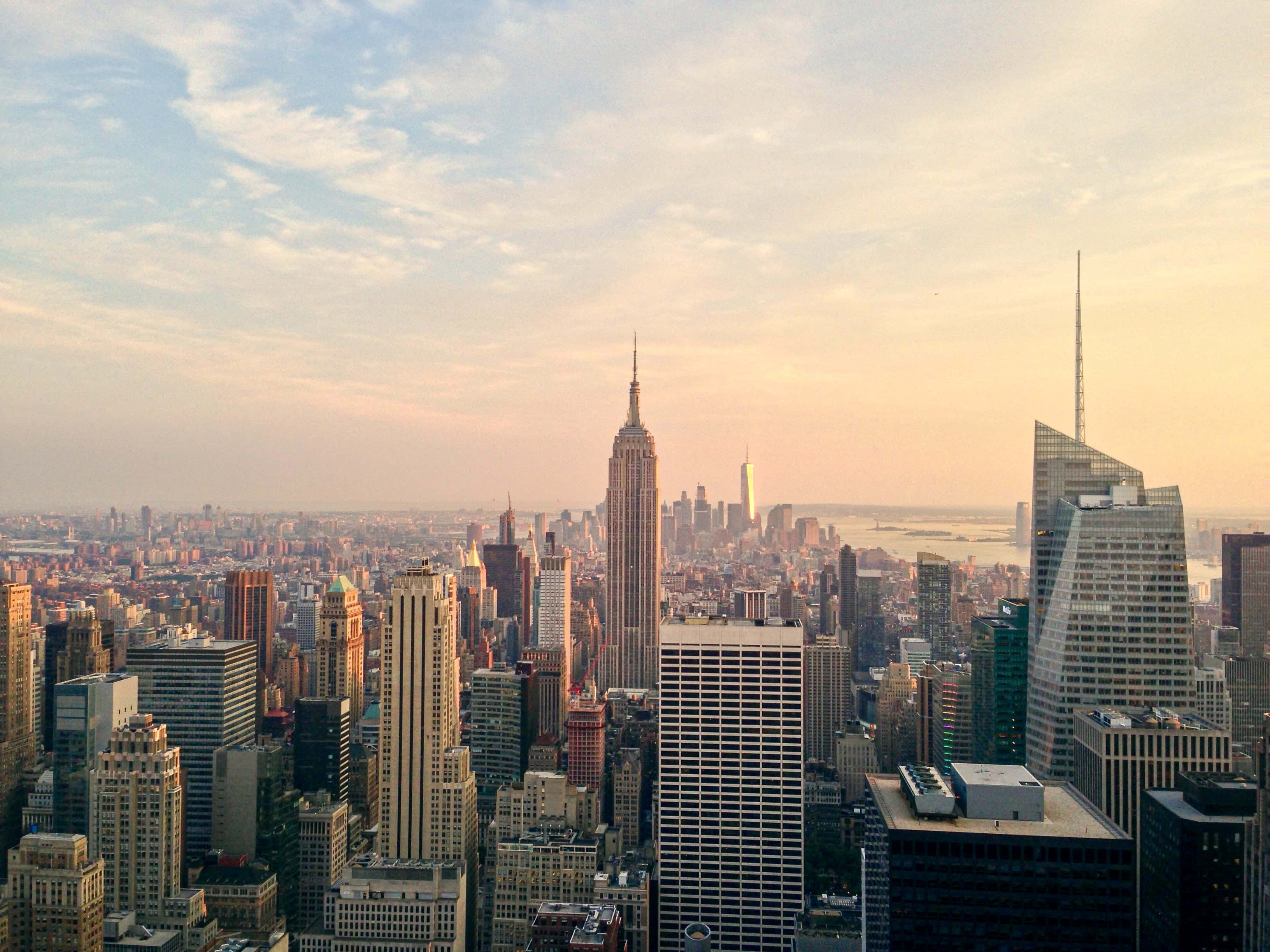 Empire State Building 桌布 壁紙 — 黃金時刻的陽光沐浴著標誌性的紐約市天際線，帝國大廈聳立在密集的城市擴展之上。