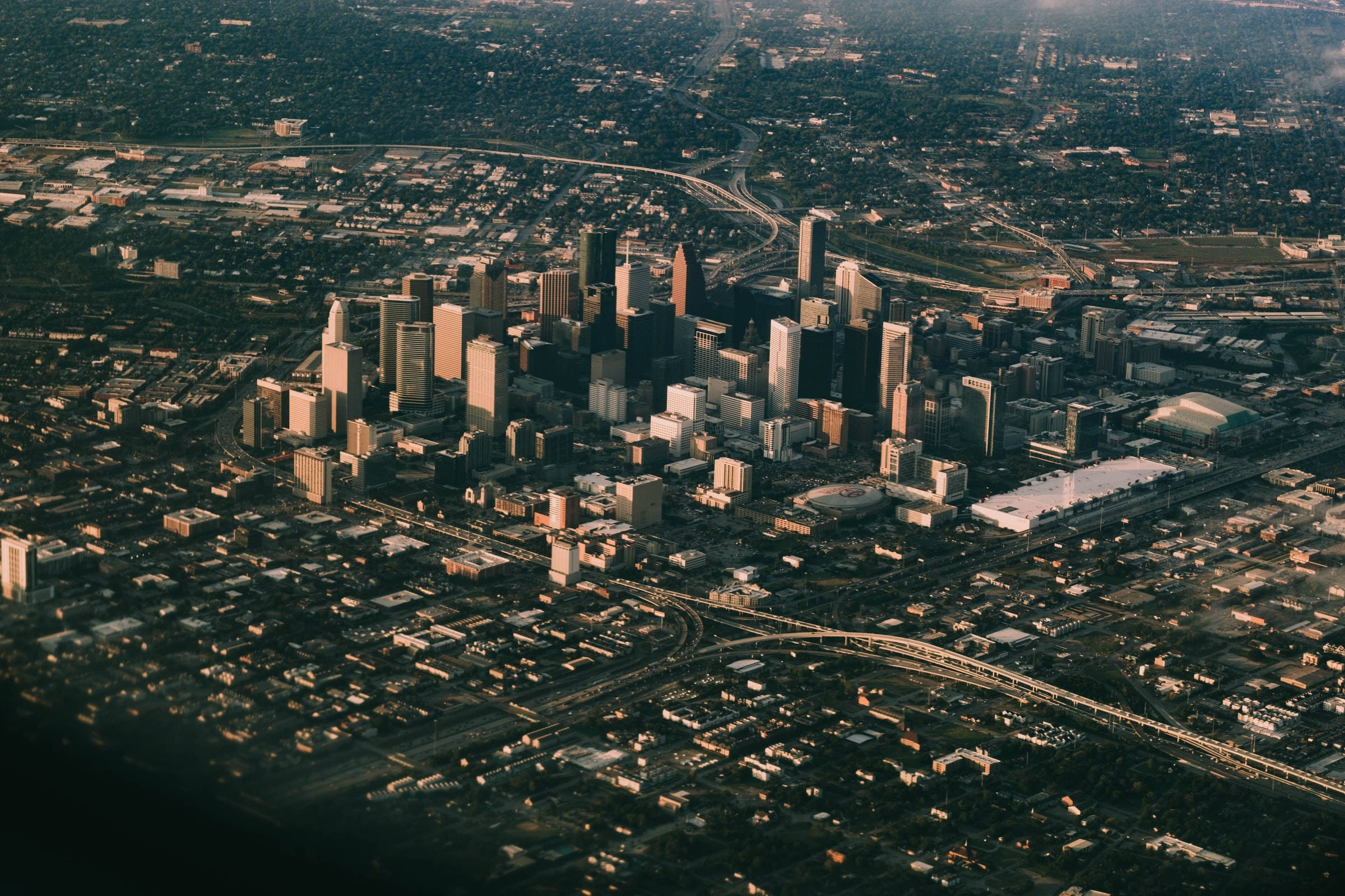 Houston 桌布 壁紙 — 黃金時段廣闊城市天際線的鳥瞰圖，高聳的摩天大樓和蜿蜒的高速公路。