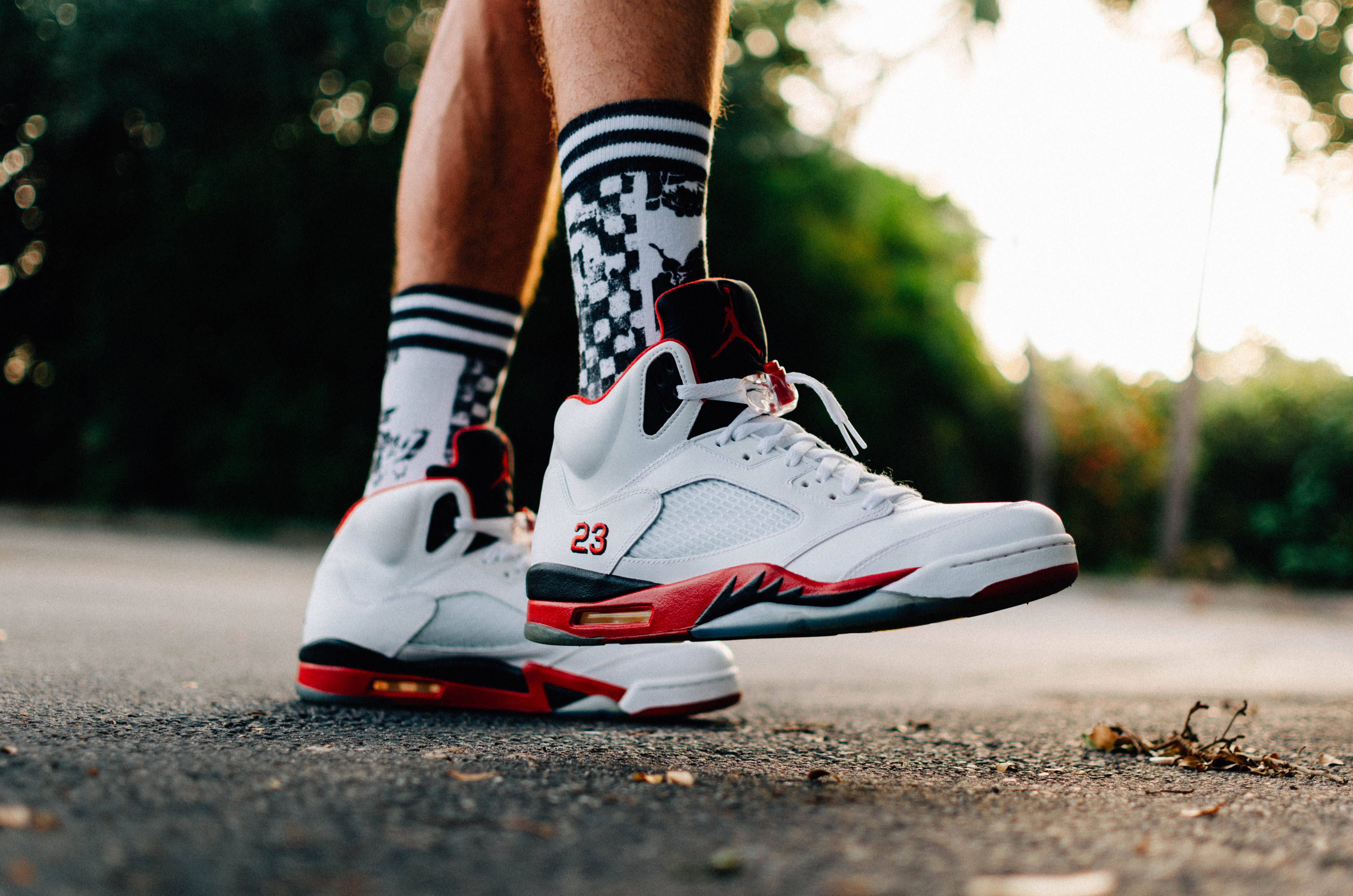 Sneaker 桌布 壁紙 — 黃金時段瀝青路上白色、紅色和黑色Air Jordan 5運動鞋配格紋襪的特寫。