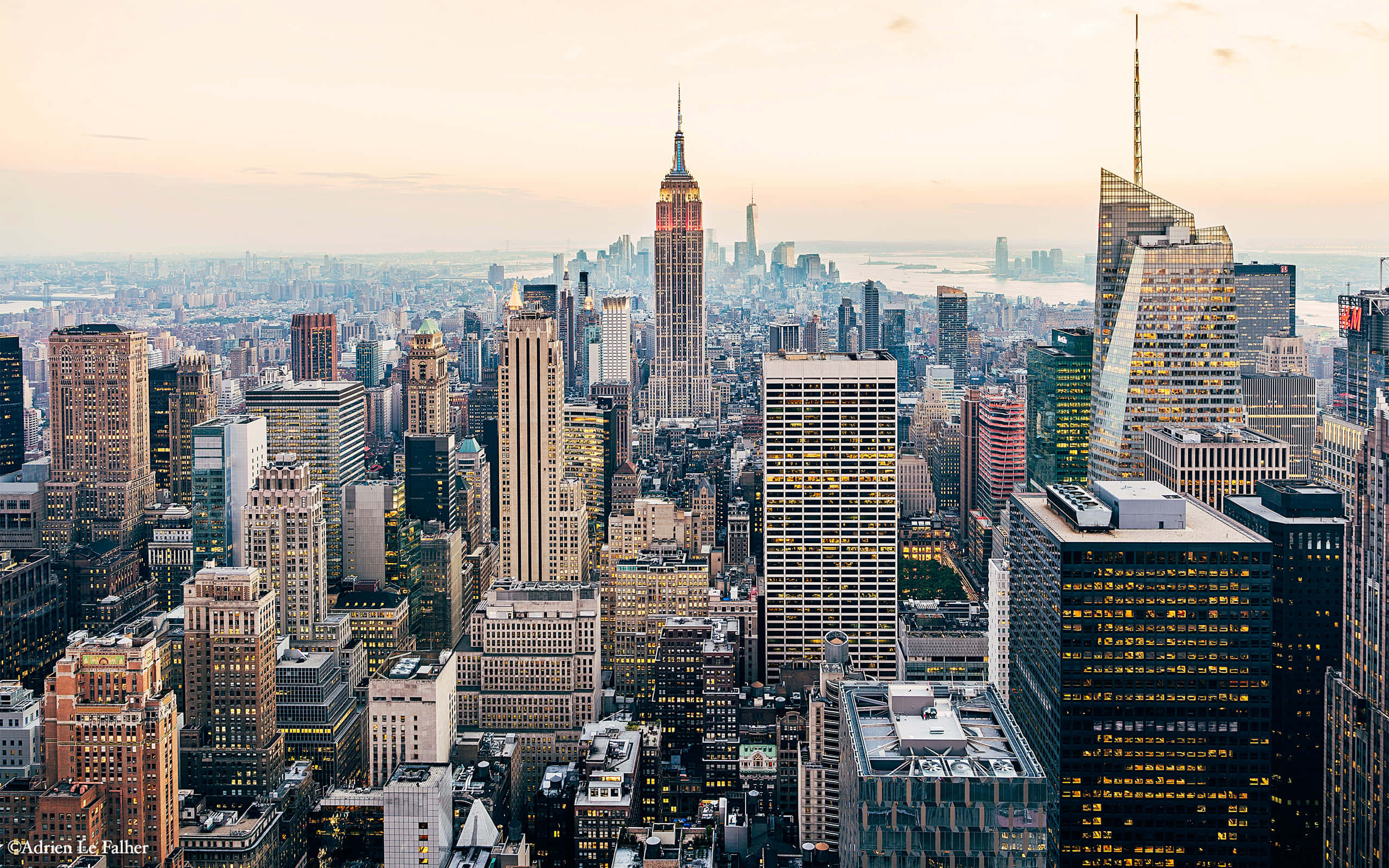 New York 桌布 壁紙 — 黃金時段紐約市天際線的鳥瞰圖，帝國大廈聳立在密集的摩天大樓和發光的窗戶之上。