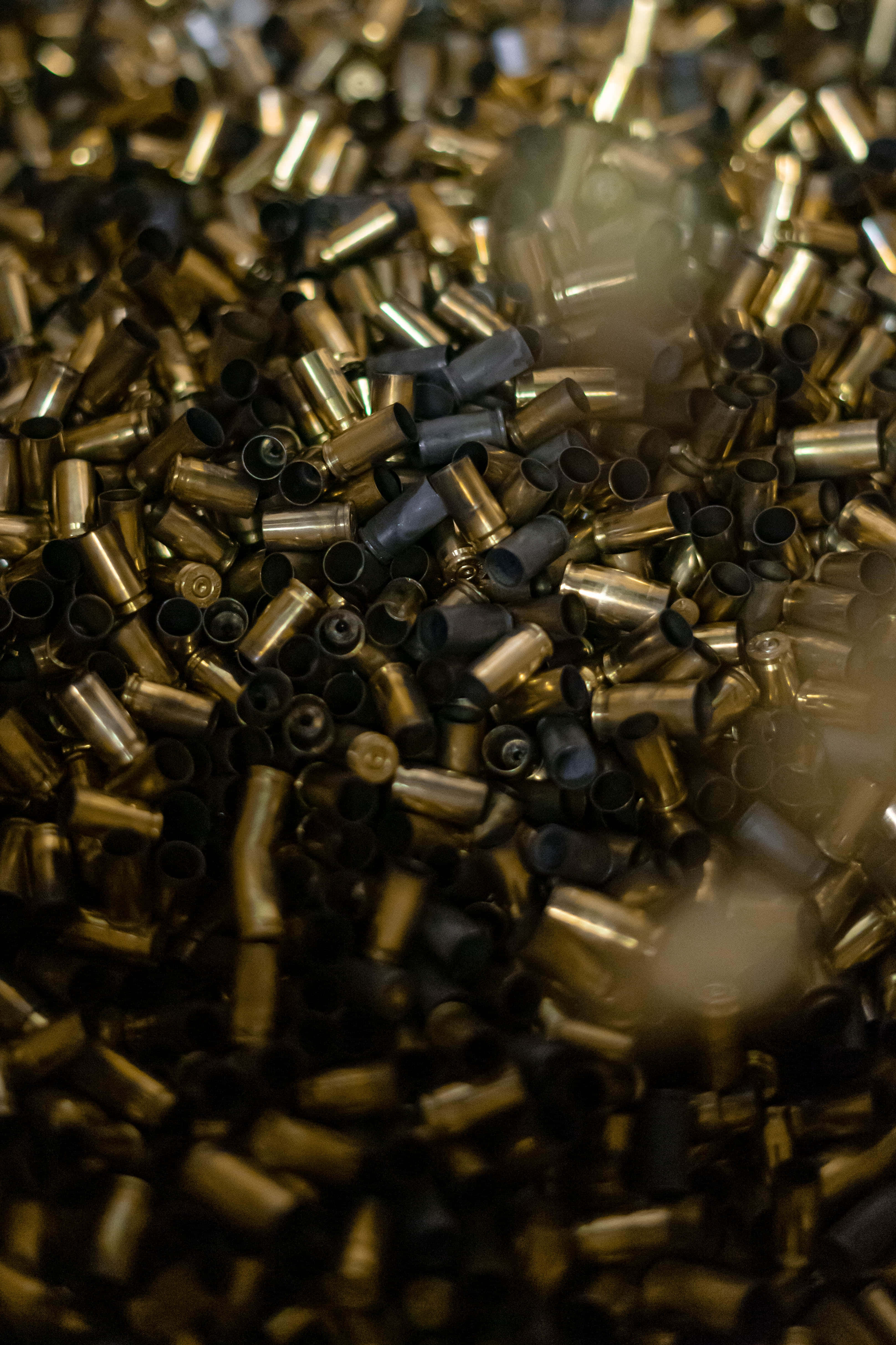 bullet 桌布 壁紙 — 黃銅和黑色子彈殼在混亂堆疊中翻滾並帶有動態模糊的特寫照片。