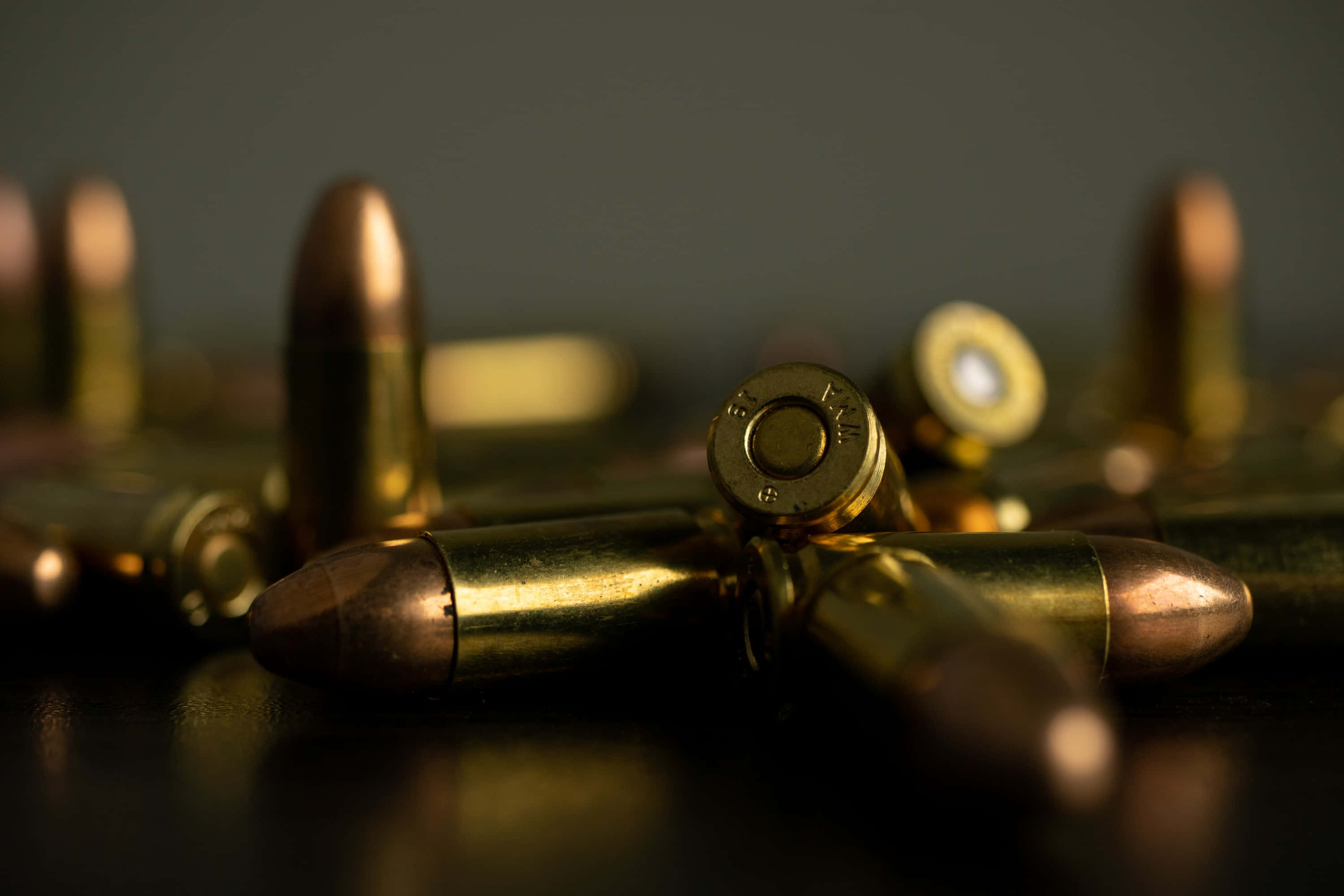 bullet 桌布 壁紙 — 黃銅子彈散落在深色表面上的特寫，景深淺，光線溫暖。
