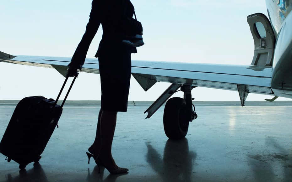Aircraft 桌布 壁紙 — 黎明時分，一位穿著高跟鞋的女性在飛機機翼旁拉著行李箱的剪影。