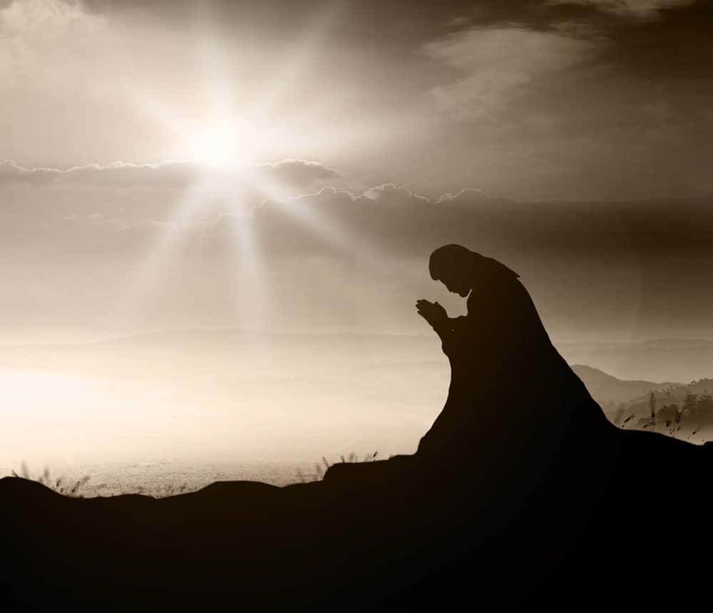 Jesus Praying 桌布 壁紙 — 黎明時分，一個人在山頂祈禱的剪影，燦爛的陽光穿透雲層。