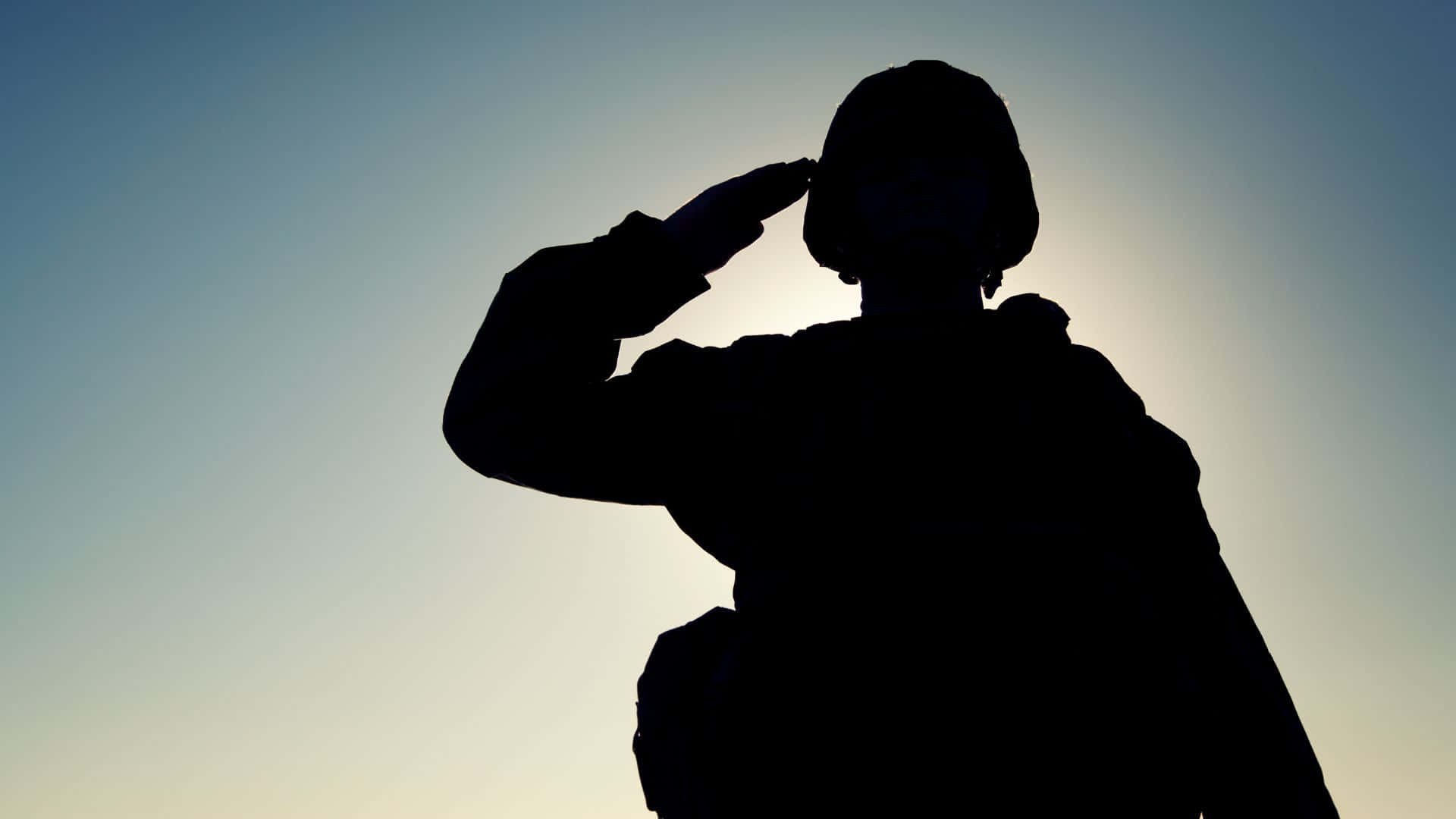 軍事動圖 桌布 壁紙 — 黎明時分，一名士兵在柔和漸變的天空下敬禮的剪影。