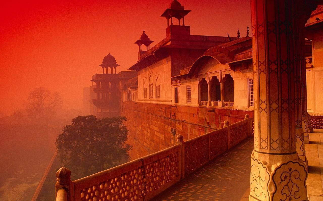 Indian 桌布 壁紙 — 黎明時分，一座歷史宮殿建築群沐浴在濃密大氣薄霧中火紅橙色的光芒中。