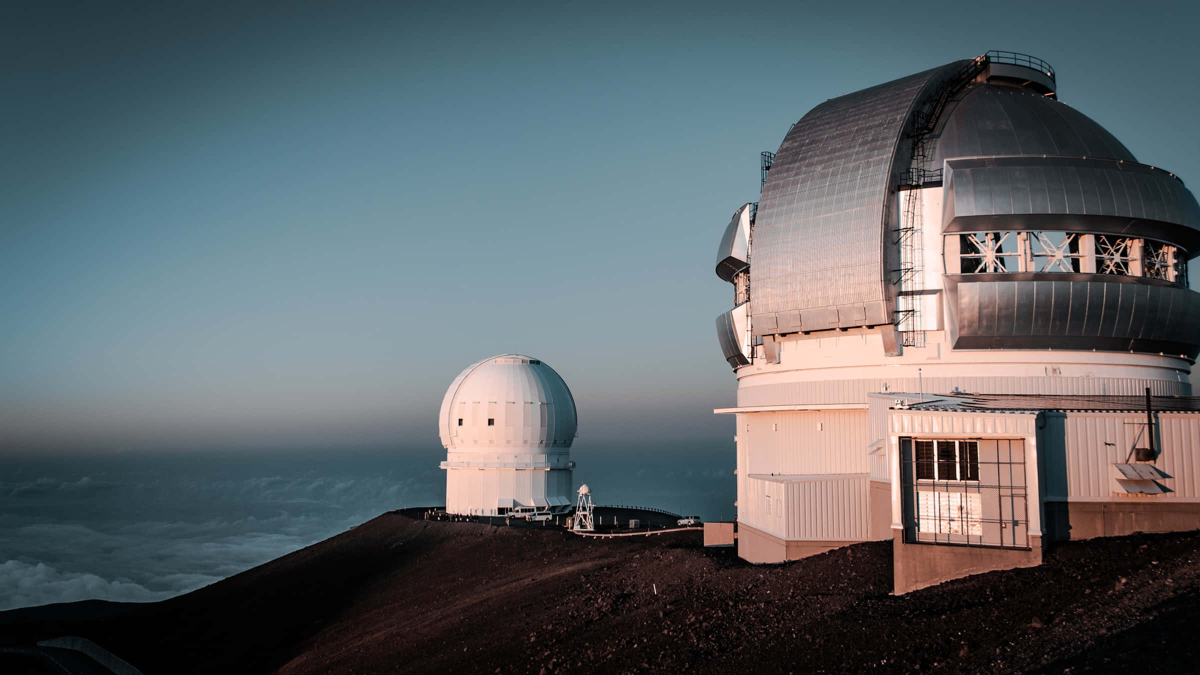 Space Observation 桌布 壁紙 — 黎明時分，兩個大型天文台圓頂矗立在火山峰頂，雲海之上。