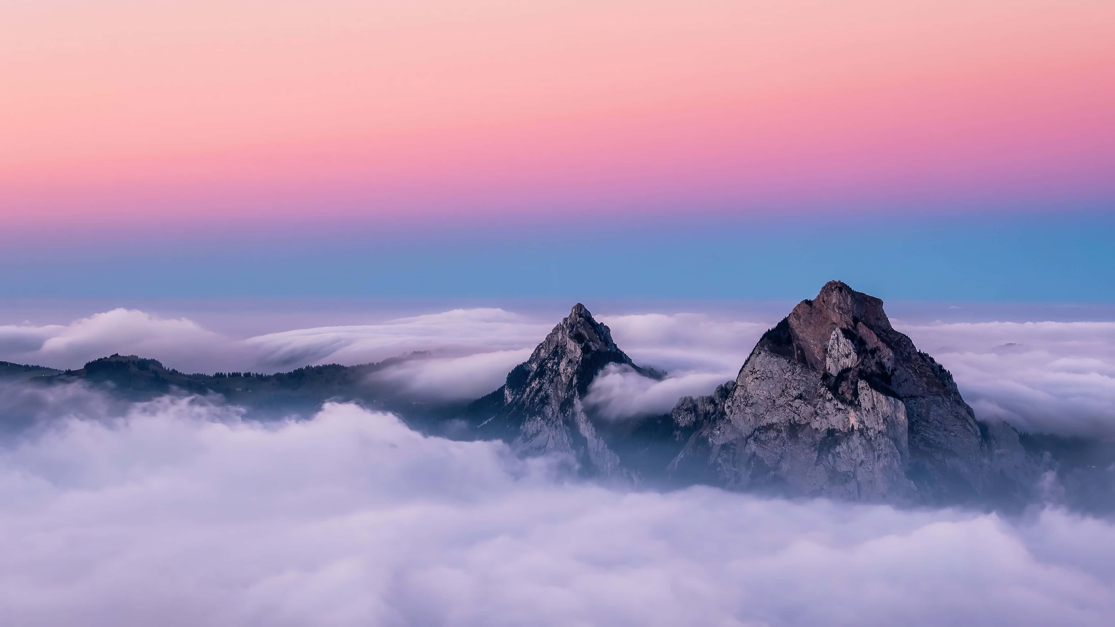 Clouds 4K 桌布 壁紙 — 黎明時分，兩座鋸齒狀山峰刺穿柔軟的雲海，天空呈現粉紅與藍色的漸變色。
