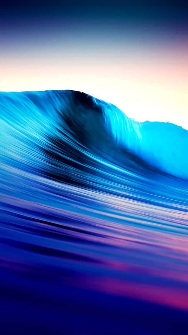 Surfing iPhone 桌布 壁紙 — 黎明時分，在帶有粉紅色和紫色色調的粉彩天空下，巨大的藍綠色波浪捲起。