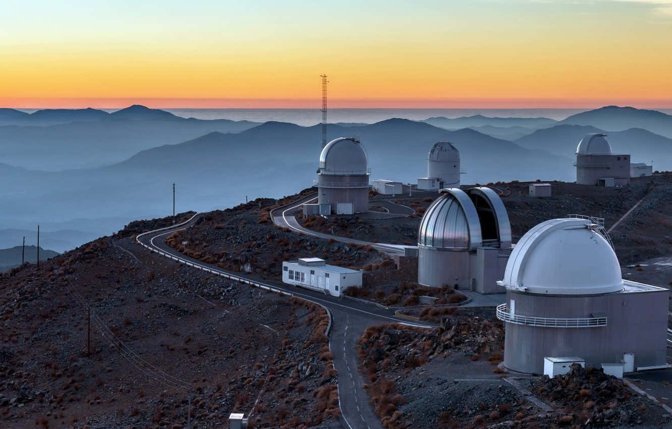 Space Observation 桌布 壁紙 — 黎明時分，望遠鏡圓頂矗立在崎嶇的山脊上，層層疊疊的山丘在下方霧氣中逐漸消失。