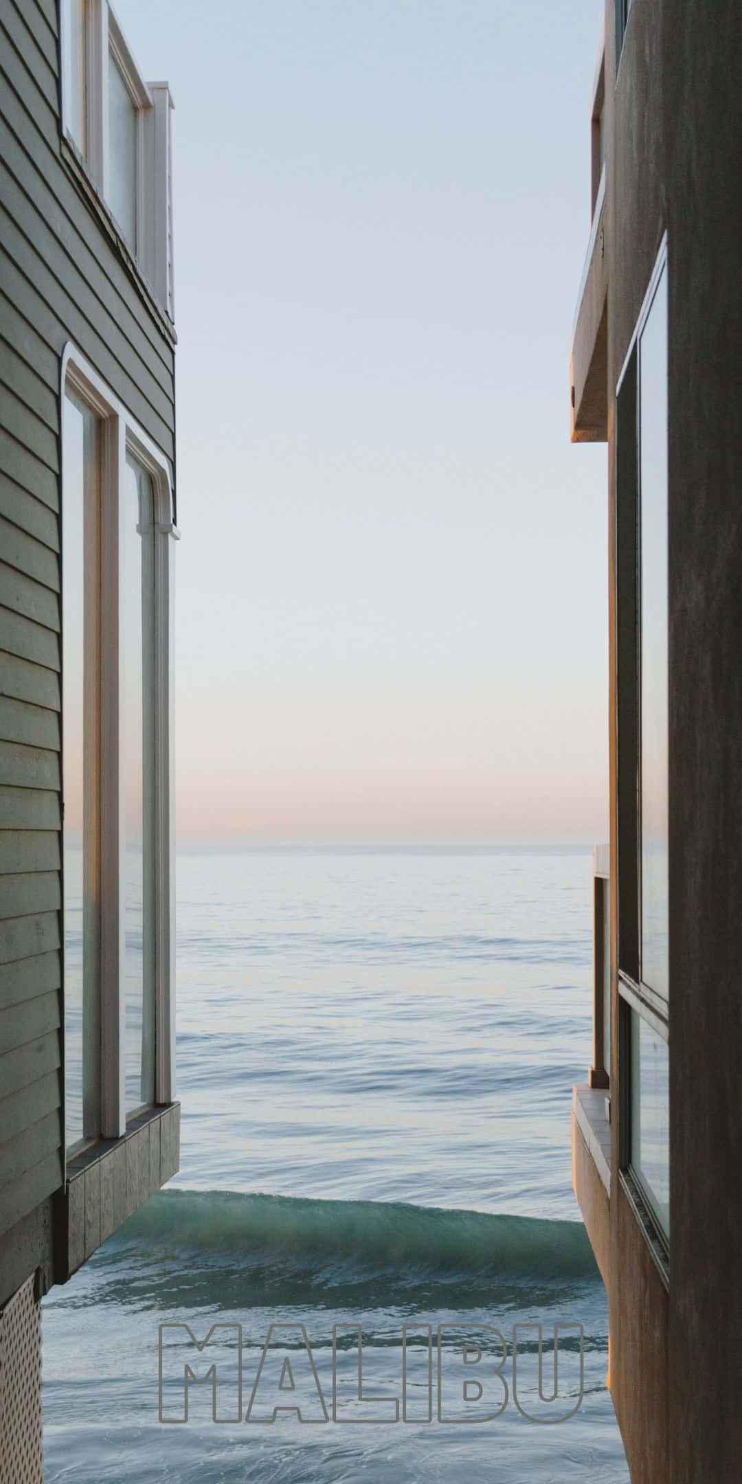 Pixel 3 Malibu 桌布 壁紙 — 黎明時分，現代房屋窗戶框住寧靜的海景，柔和粉彩天空與輕柔海浪。