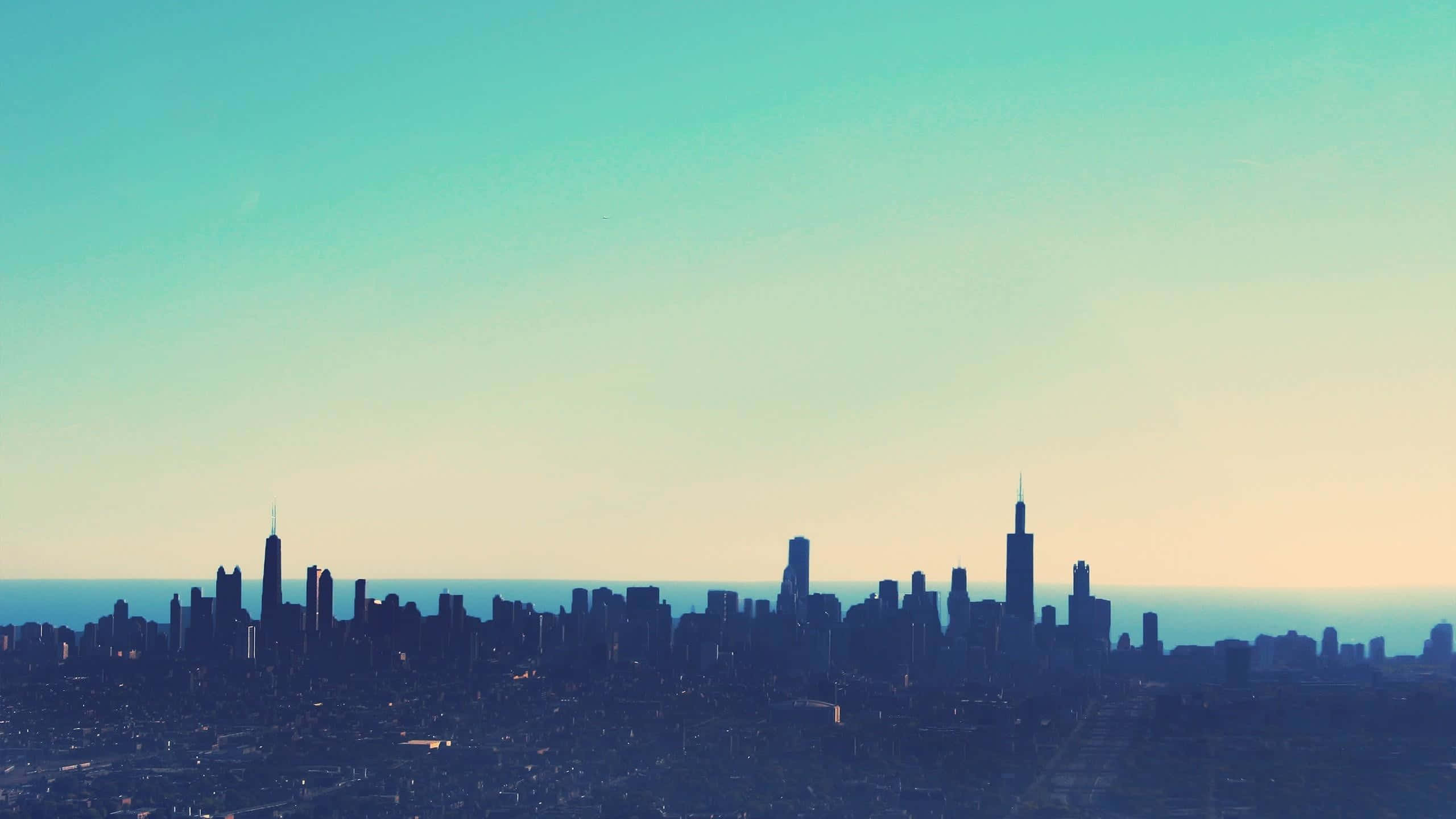 Chicago Skyline 桌布 壁紙 — 黎明時分寧靜的城市天際線，摩天大樓的剪影映襯著青綠色和蜜桃色的漸變天空。
