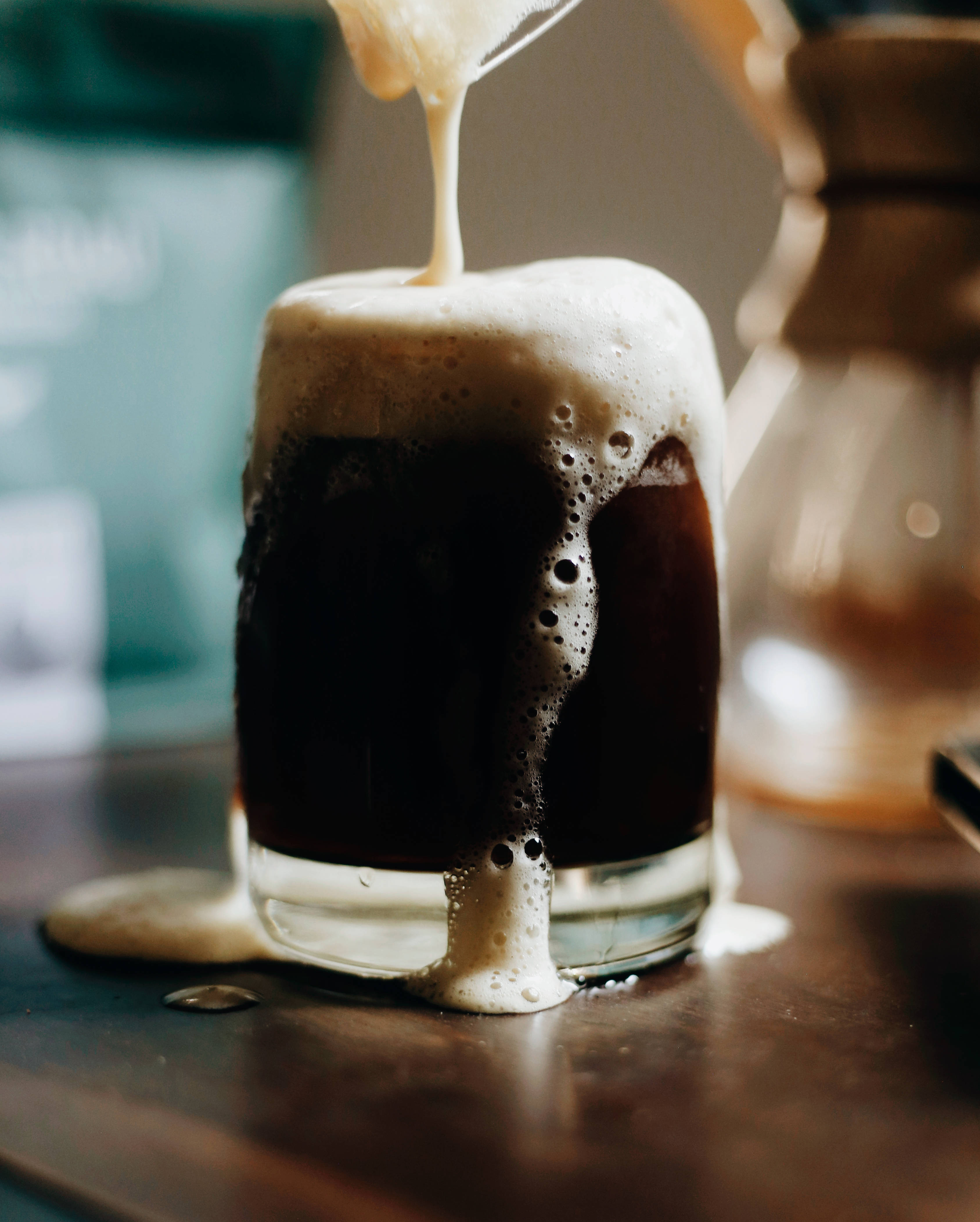 Beer 桌布 壁紙 — 黑啤酒倒入玻璃杯，產生濃厚奶油狀泡沫，溢出杯緣流到木質表面。