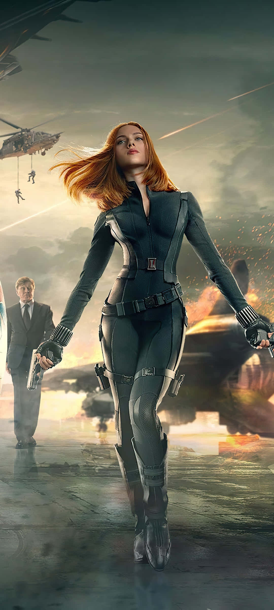Captain America Movie 桌布 壁紙 — 黑寡婦自信地穿著戰術裝備行走，身後爆炸和直升機在戰火摧殘的城市戰場中肆虐。