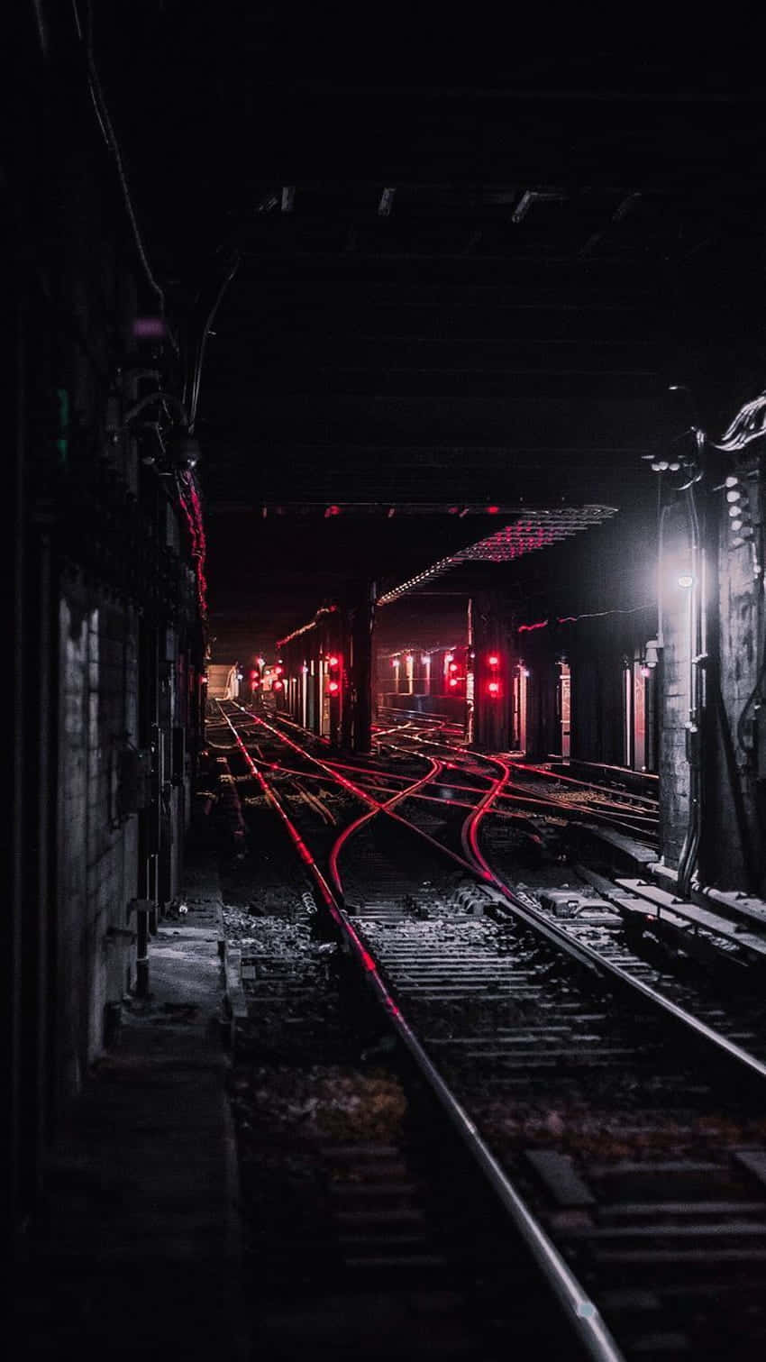 train tunnel 桌布 壁紙 — 黑暗廢棄的鐵路軌道在隧道內昏暗的頂燈下閃爍著紅色的信號。