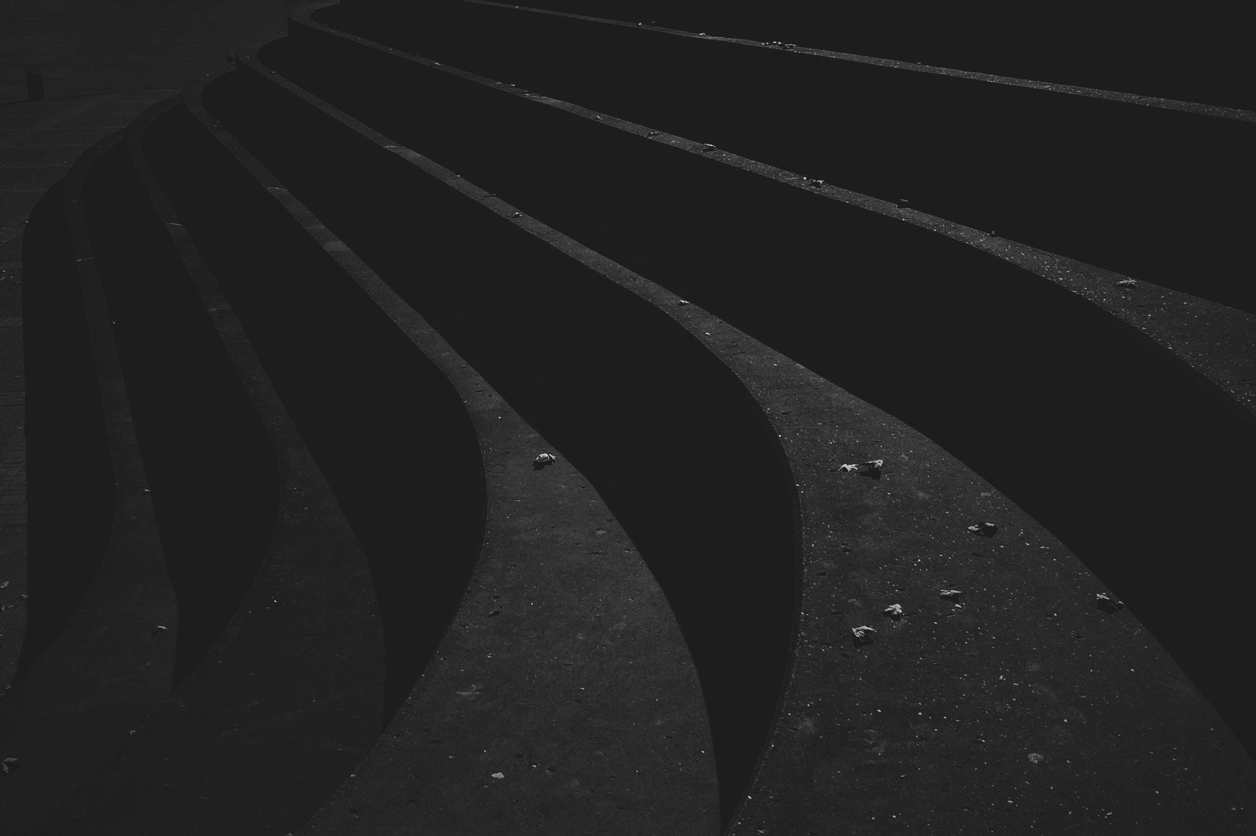 dark black 桌布 壁紙 — 黑暗彎曲的混凝土階梯在強烈光線下退入陰影，散落著碎片。